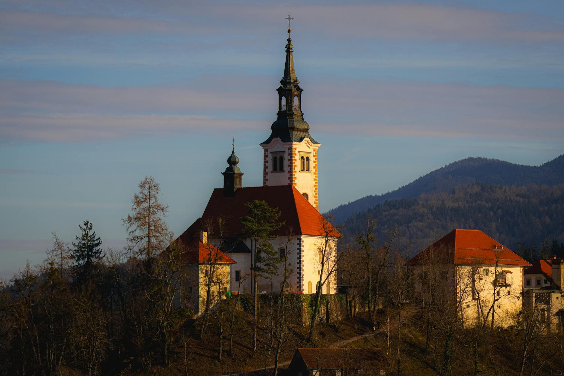 Picturesque view of a historic church in Radovljica, Slovenia during sunset with mountain backdrop.