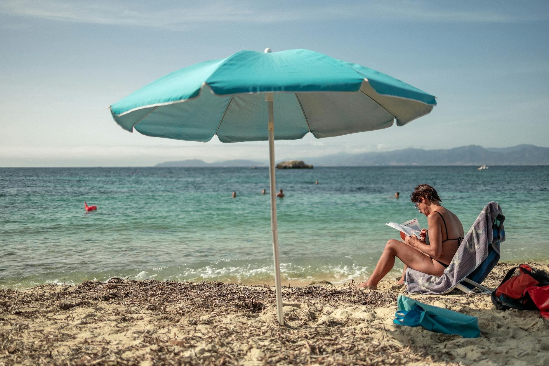 Enjoy a tranquil day on a Sardinian beach with sunbathing, reading, and scenic views.
