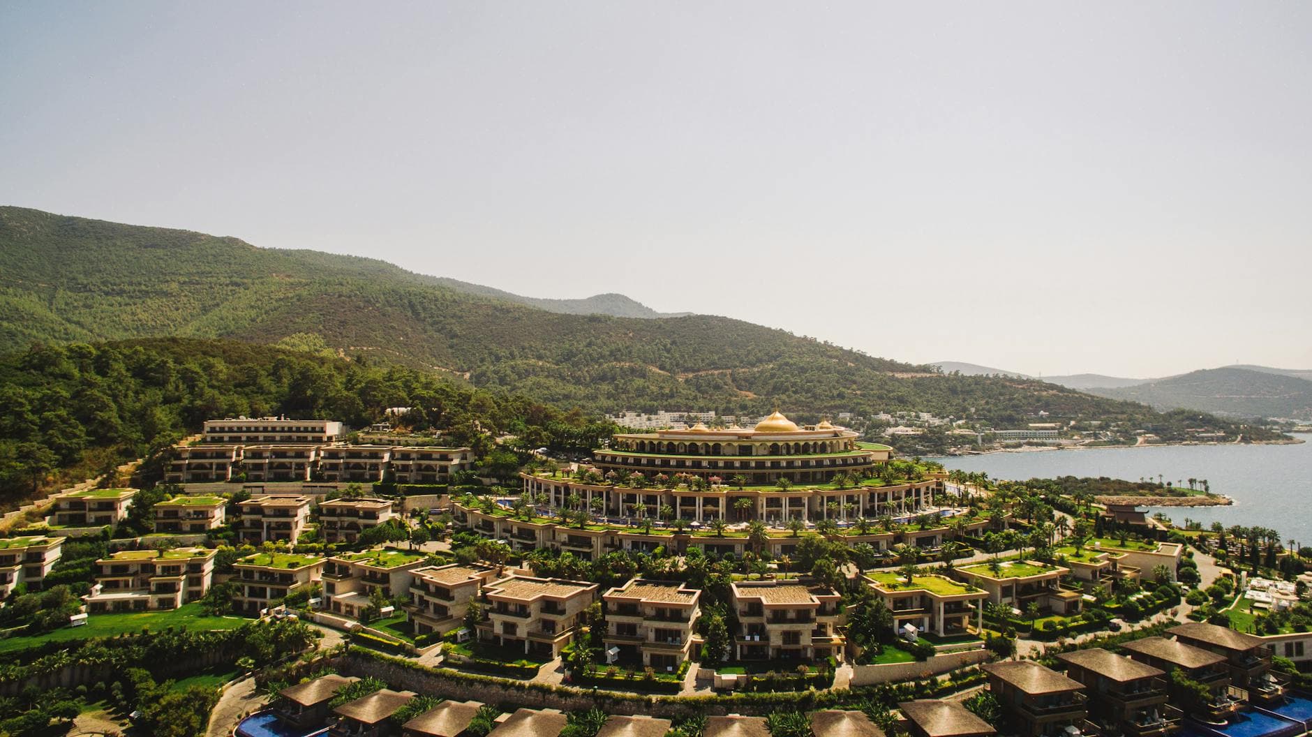 Stunning aerial view of a luxurious resort by Torba Bay amid lush hills in Bodrum, Turkey.