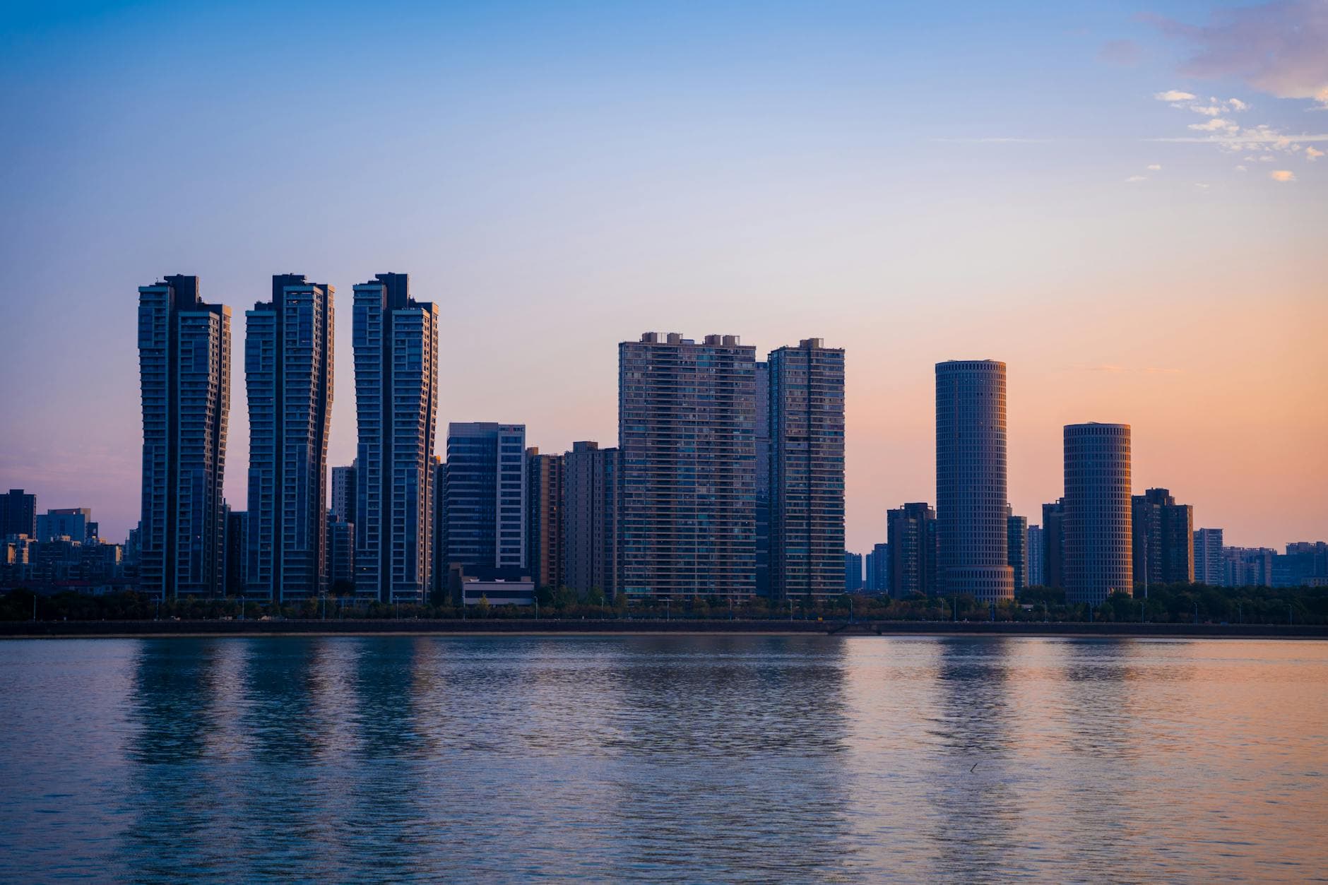 Stunning view of Hangzhou's skyline at sunset, showcasing modern skyscrapers and serene waters.
