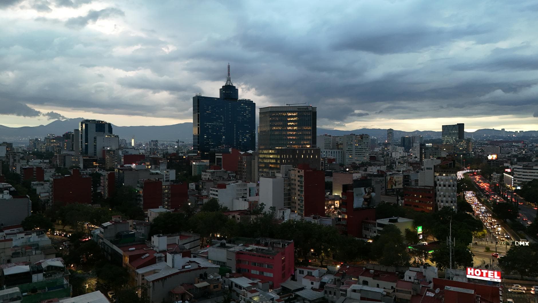 Dramatic view of Mexico City's skyline during sunset showcasing high-rise buildings and busy streets.