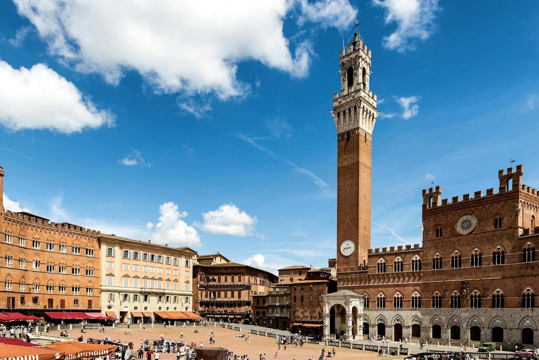Historic cityscape of Siena's Piazza del Campo featuring the iconic Torre del Mangia under blue skies.