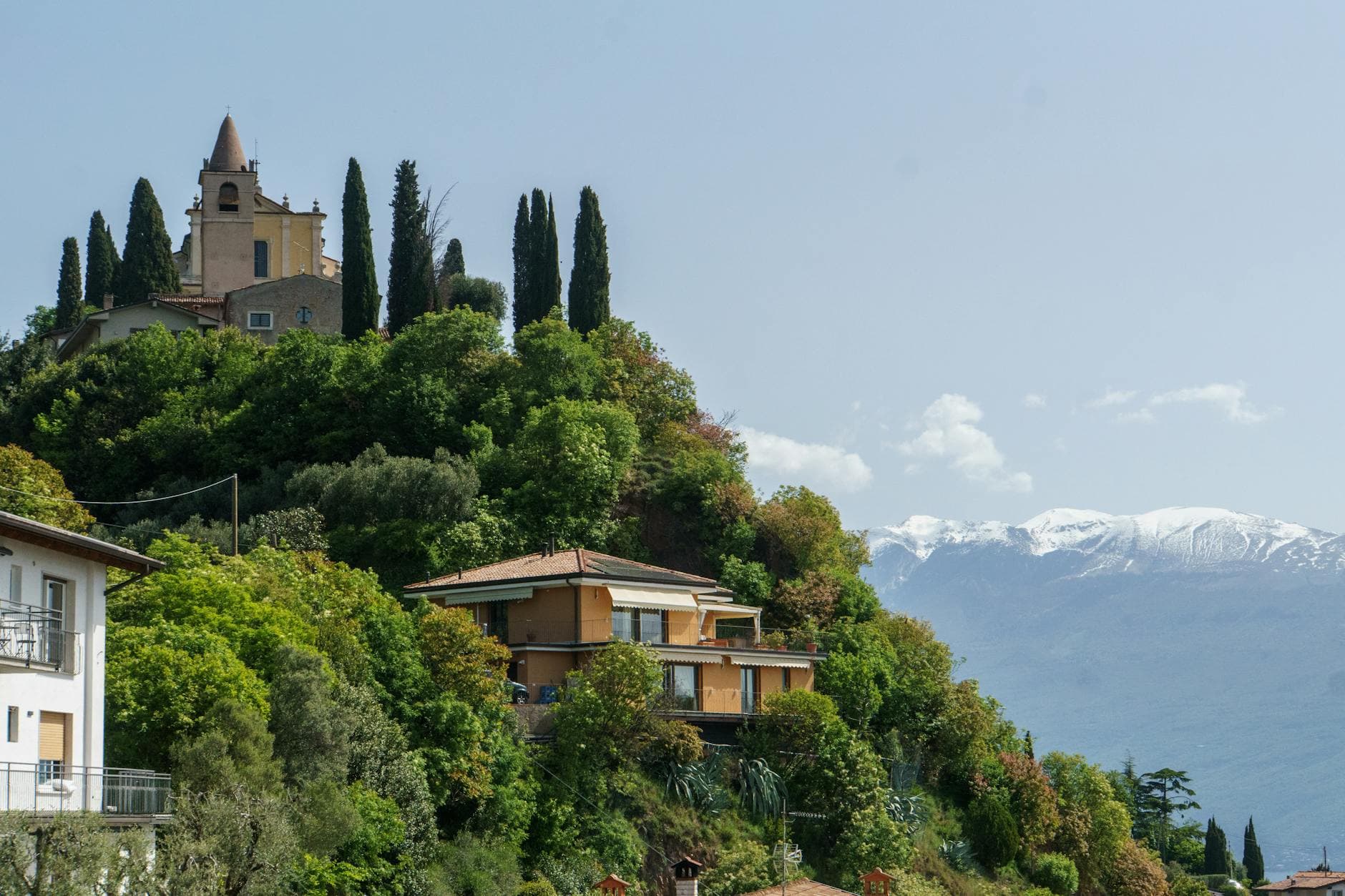 Hillside view of Toscolano Maderno featuring historic church and houses with mountain backdrop.