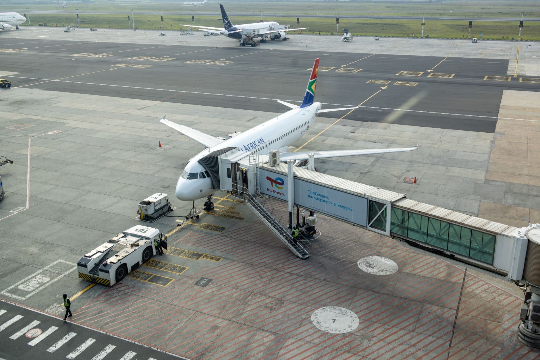 South African Airways plane docked at a gate in an airport, captured from an aerial view.