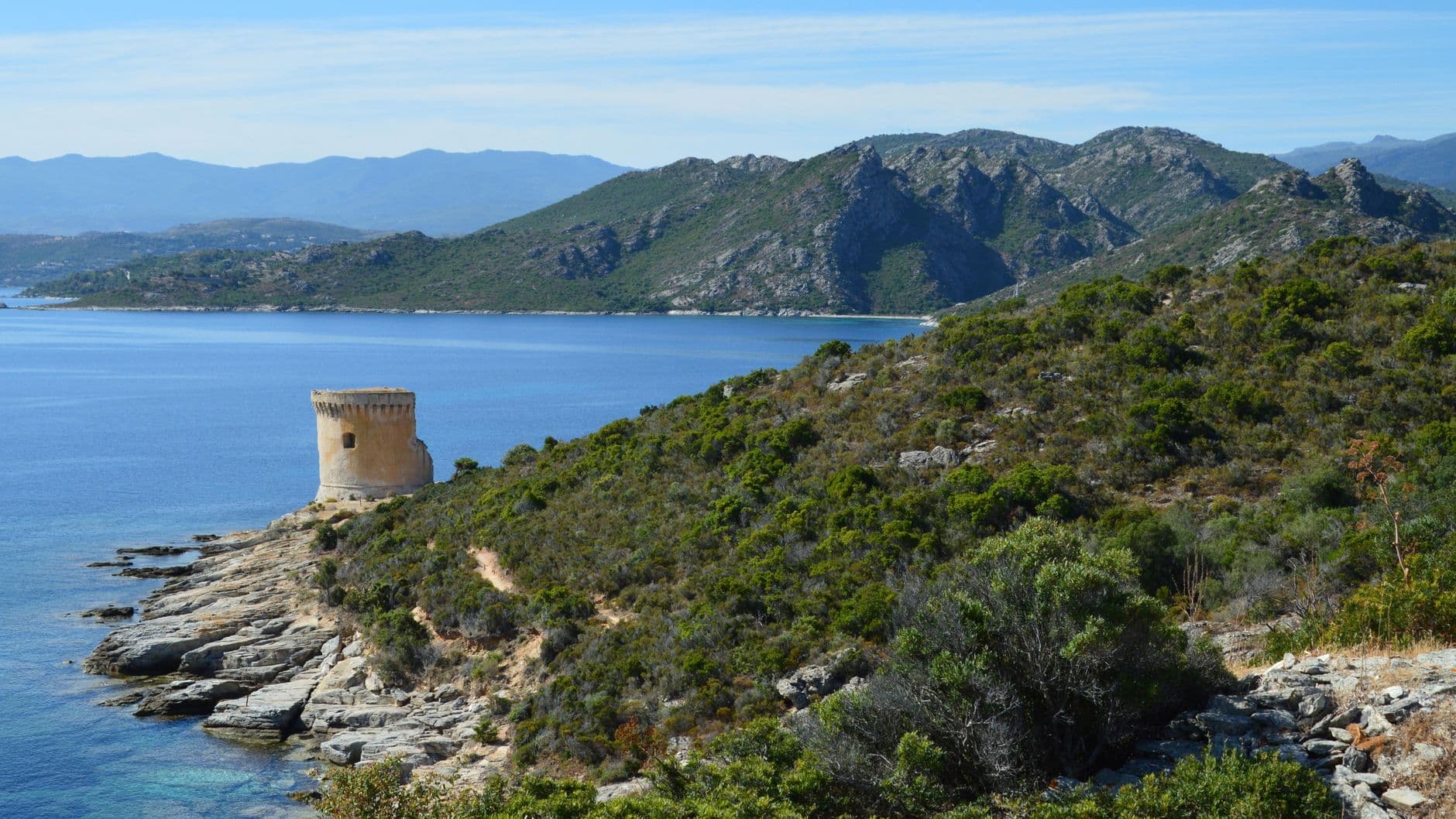 Captivating view of the Corsican coastline with a historic tower and lush landscapes.
