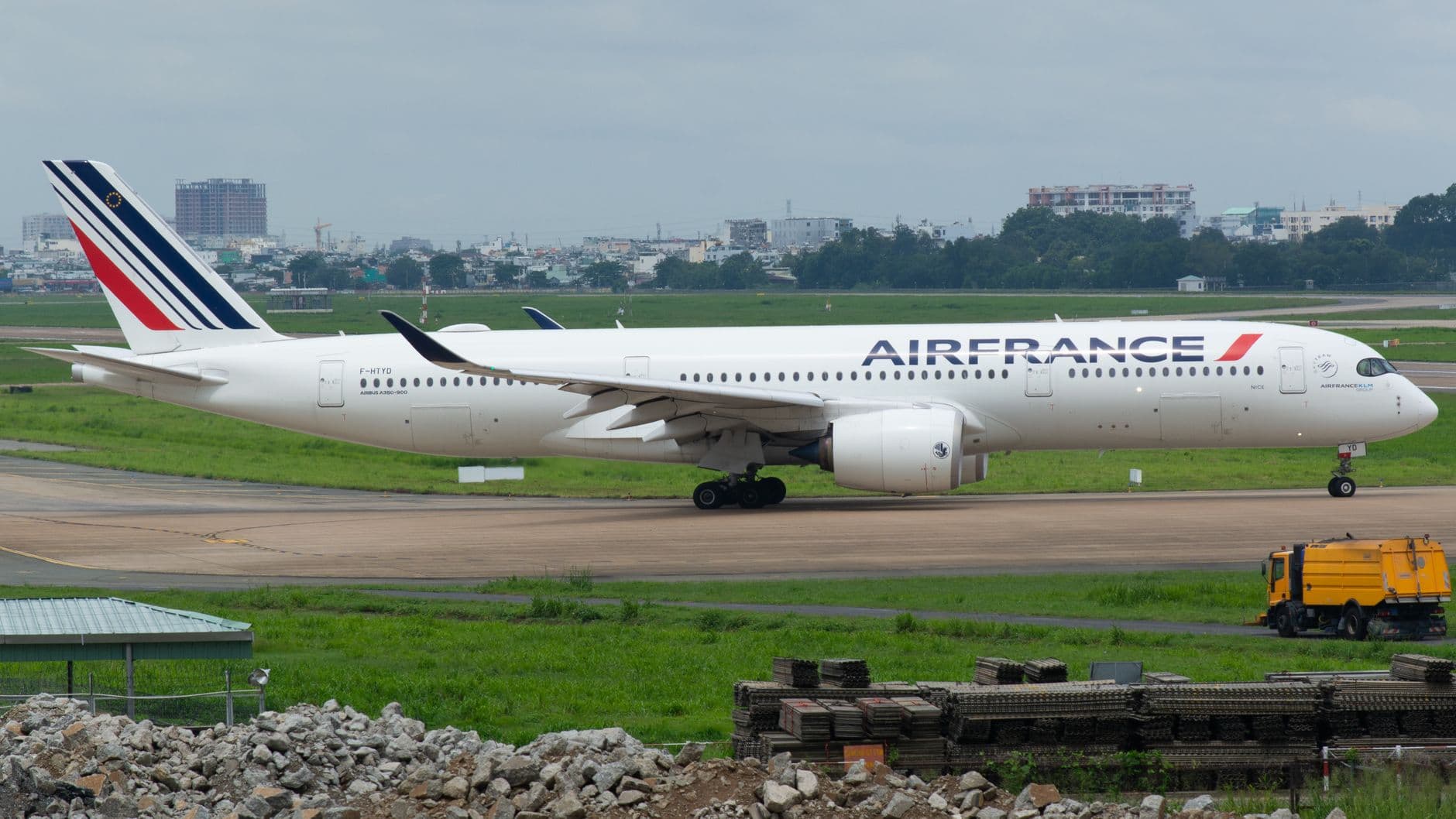 Air France Airbus A350 aircraft parked on runway with cityscape background.