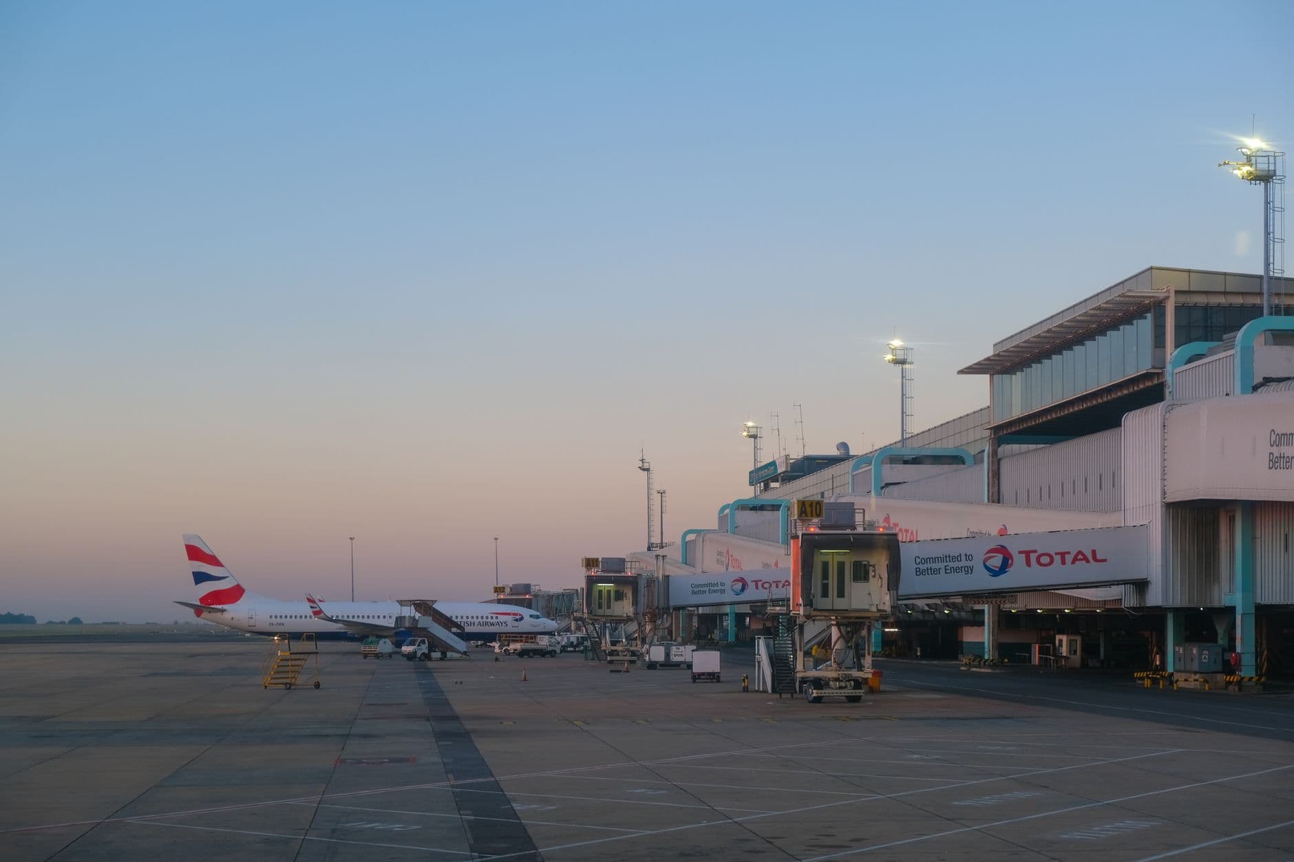 Sunset view of airplanes at the airport terminal with boarding bridges.