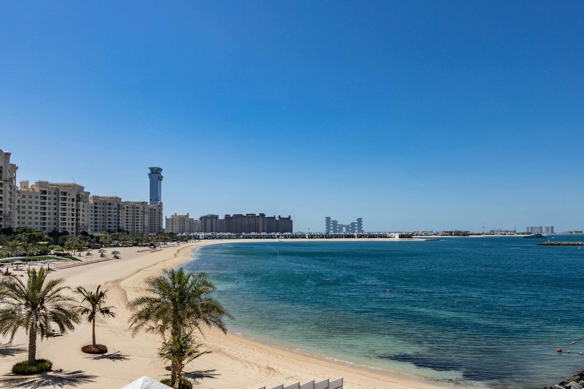 Scenic view of Palm Jumeirah beach and skyline in Dubai, UAE with clear blue skies.