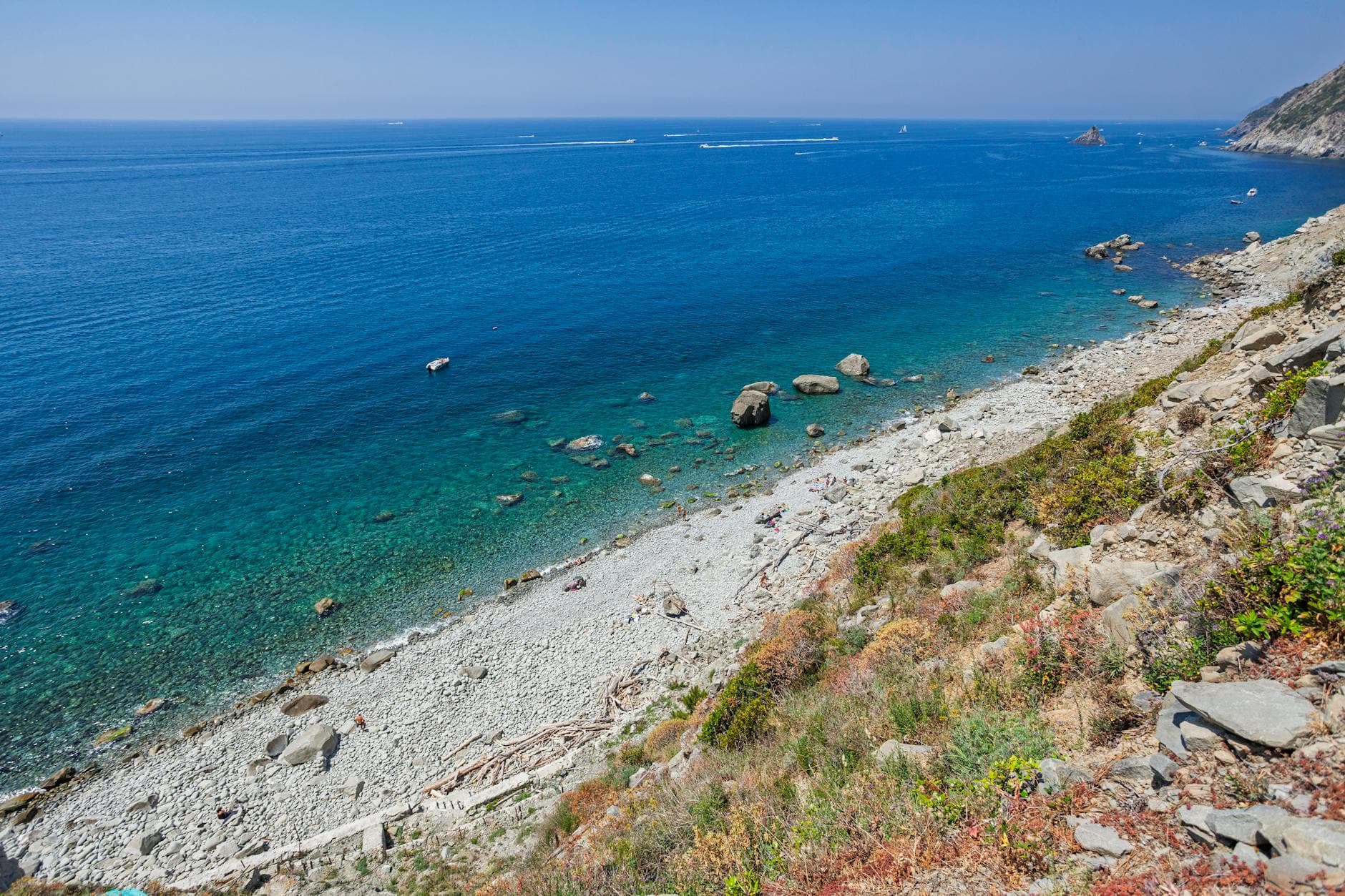 Stunning seaside view from Riomaggiore, highlighting clear blue waters and rocky beach.