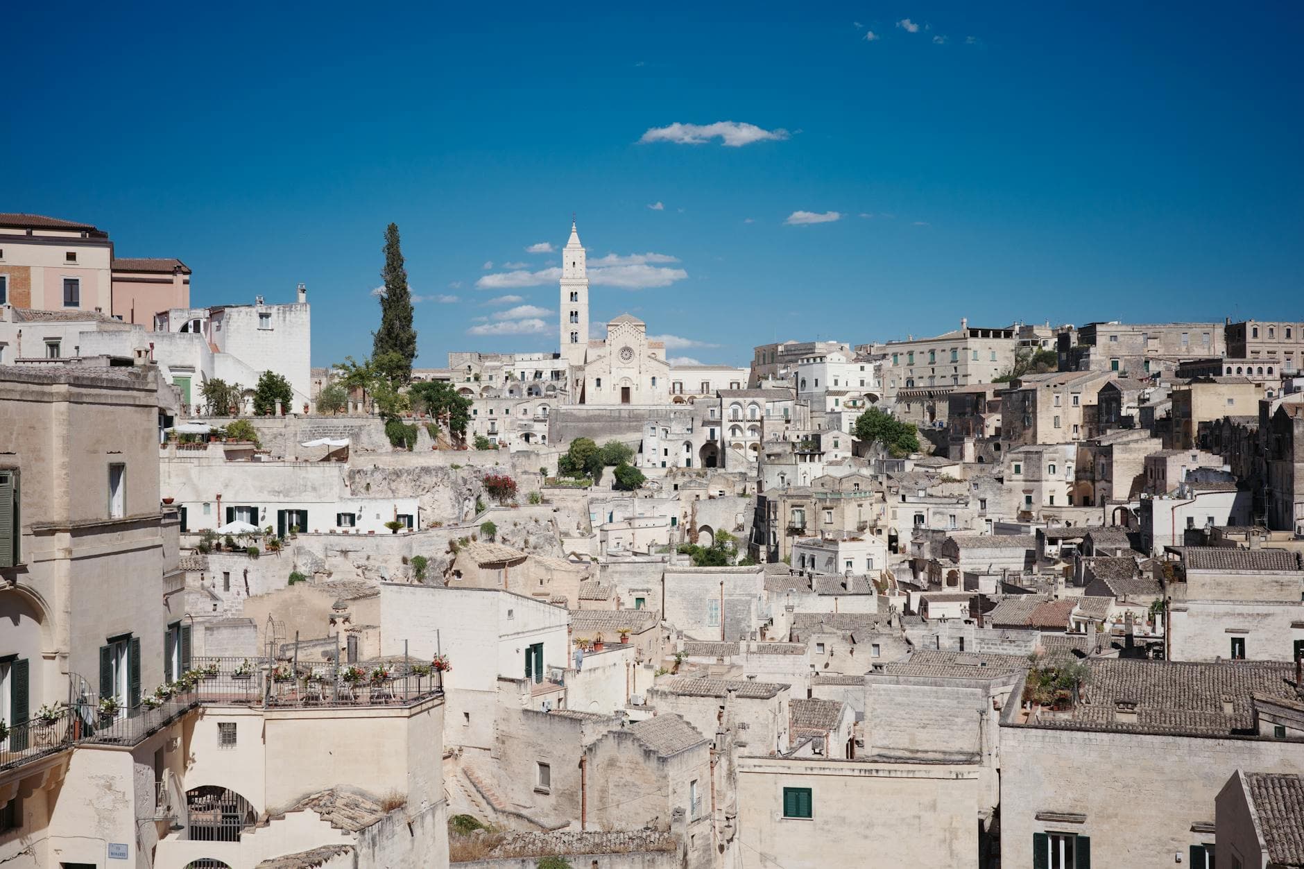 Stunning view of the ancient stone cityscape of Matera under a clear blue sky, showcasing historic architecture.