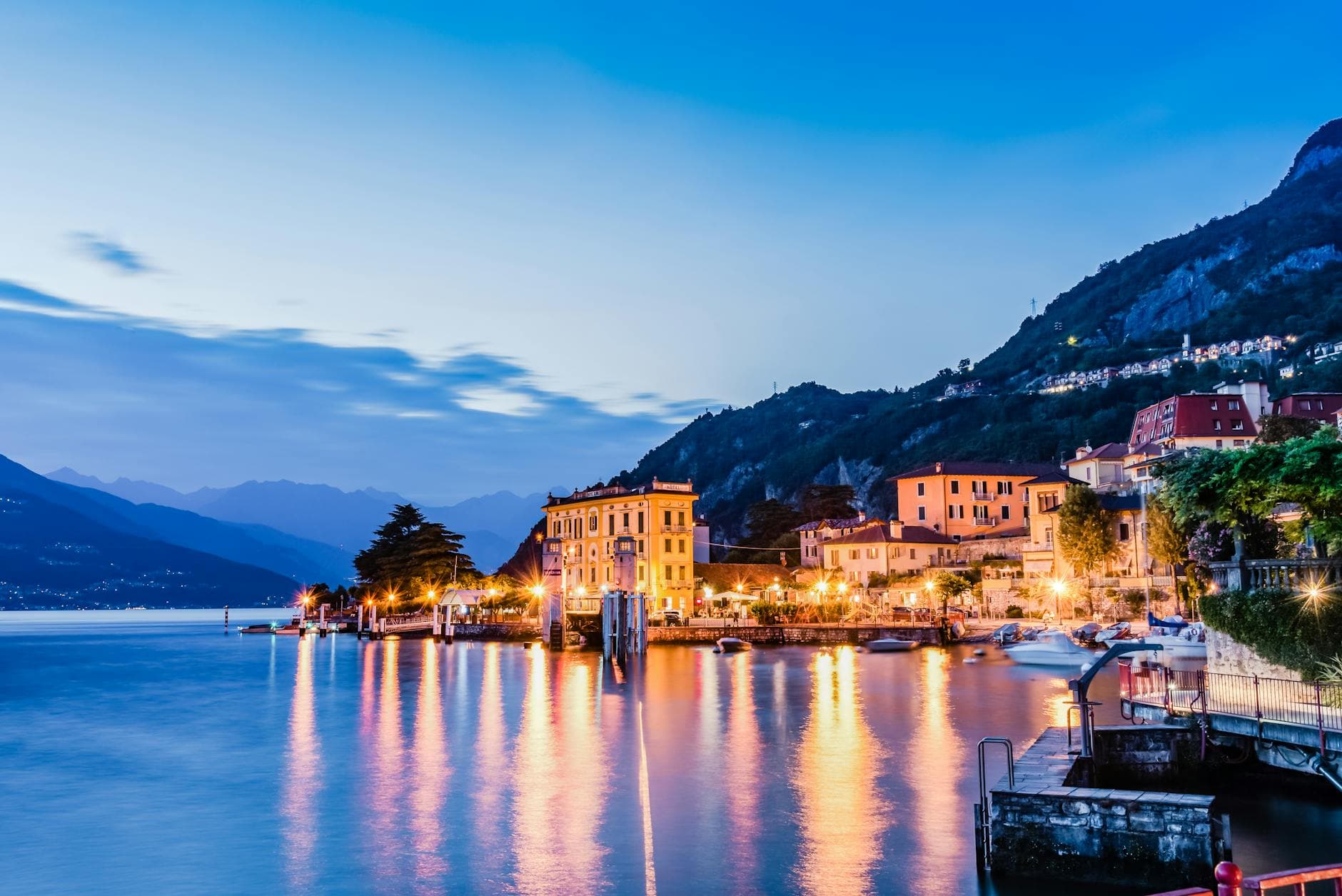 Breathtaking twilight view of Lake Como in Lombardy, Italy, showcasing vibrant waterfront buildings and serene waters.