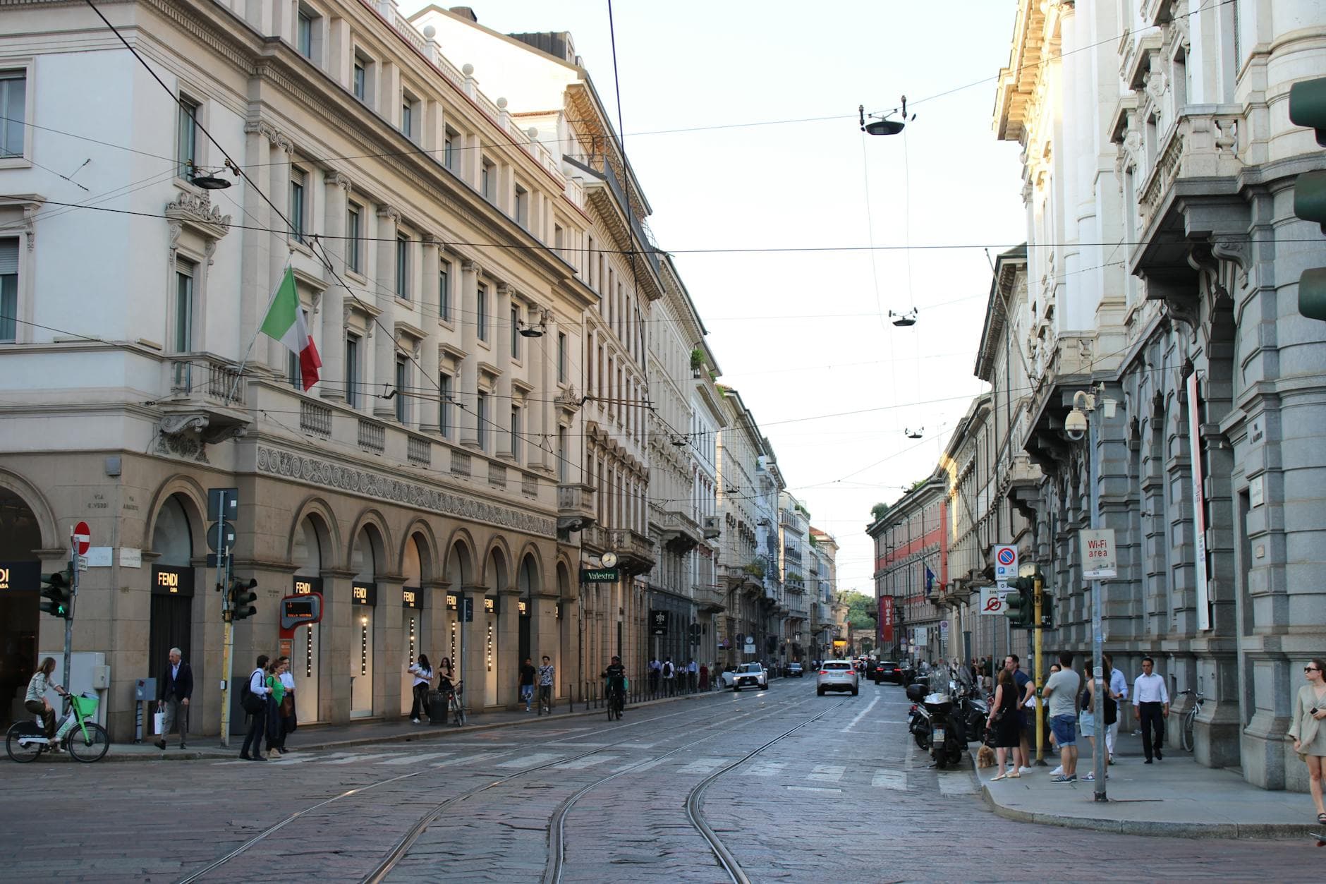 View of a bustling street in Milan, Italy featuring charming historic architecture and city life.