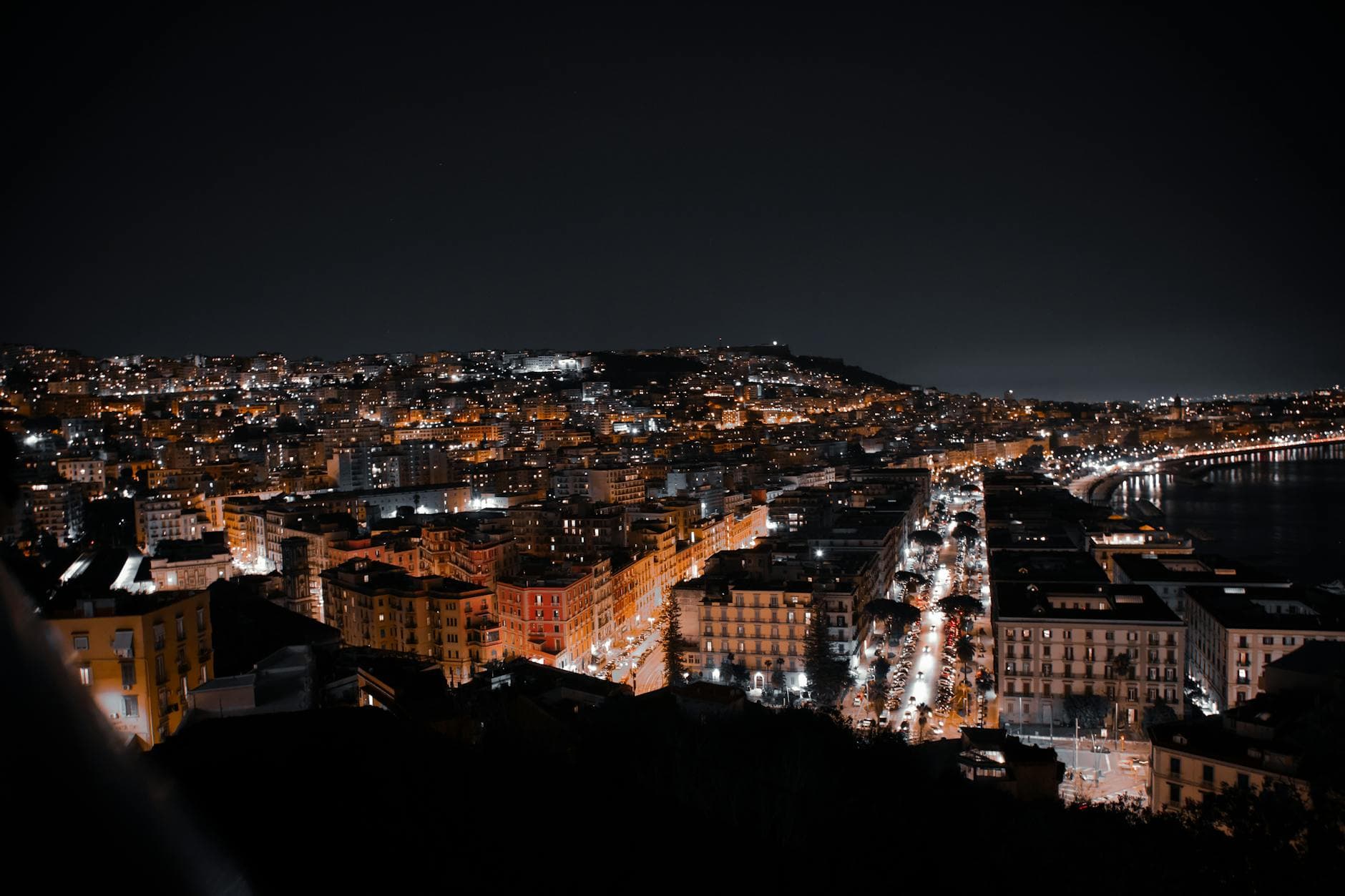 Captivating night skyline of Naples showcasing illuminated buildings and streets.