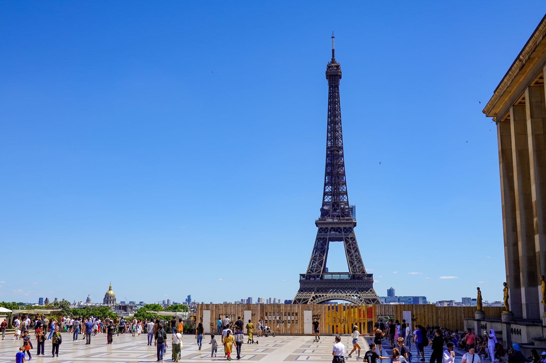 Eiffel Tower stands majestically against a clear blue sky with tourists and Paris skyline.