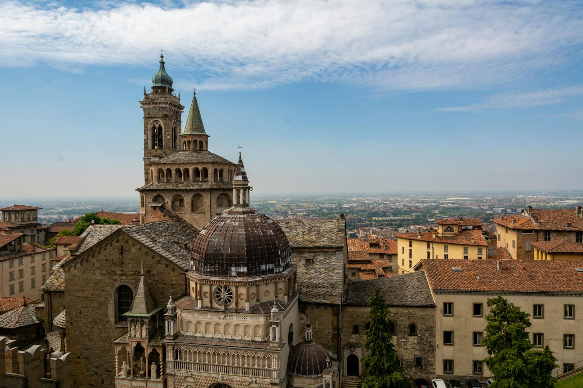 Aerial view of the historic Bergamo Cathedral in Italy under a bright blue sky.
