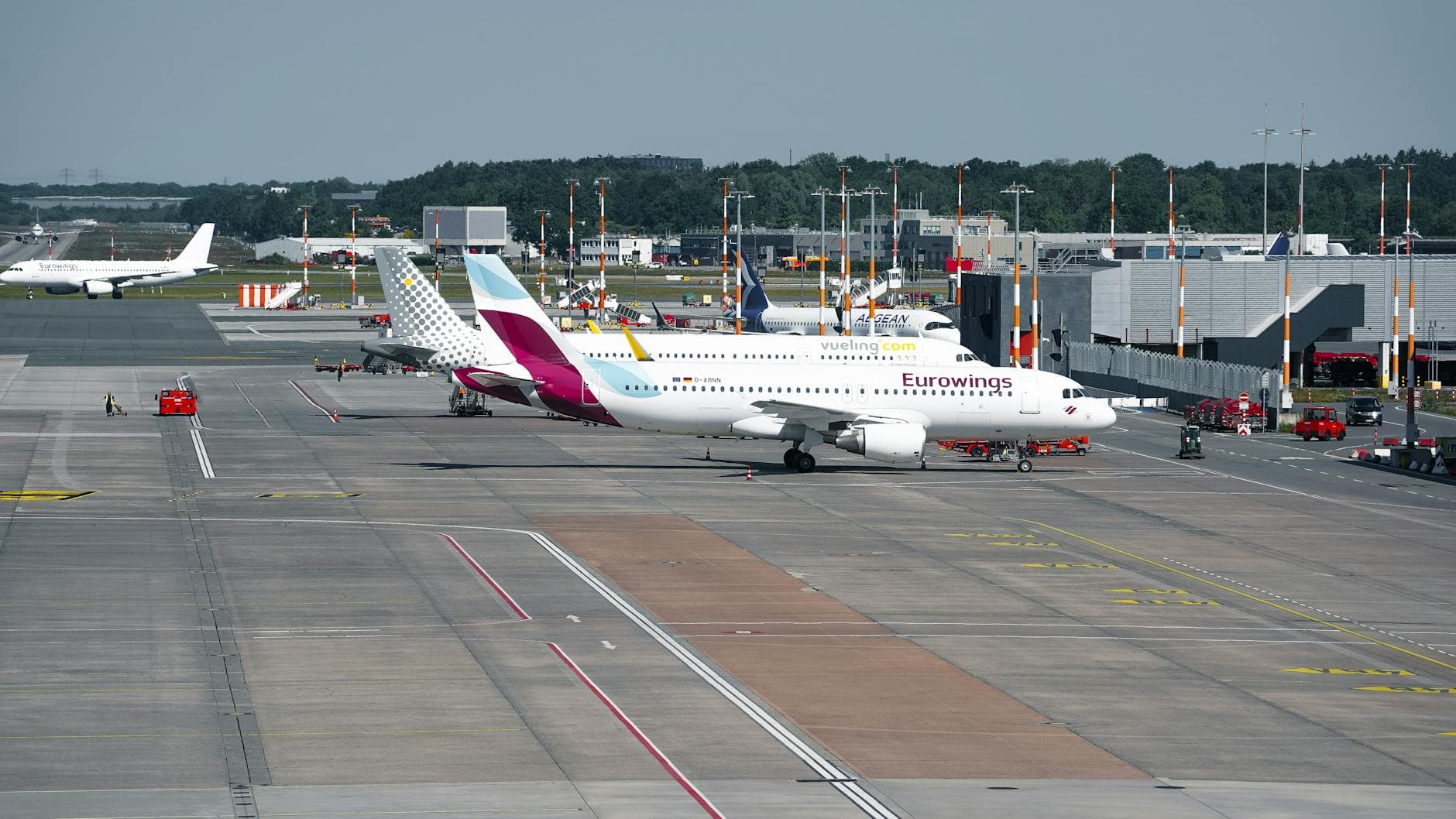 Wide-angle view of a bustling airport in Hamburg featuring Eurowings aircraft on the taxiway.