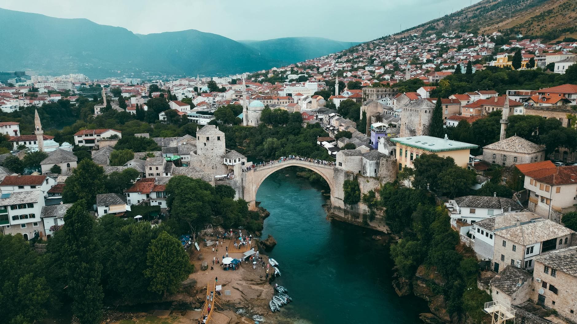 A stunning aerial shot of Mostar's historic Old Bridge surrounded by the scenic cityscape and lush greenery.