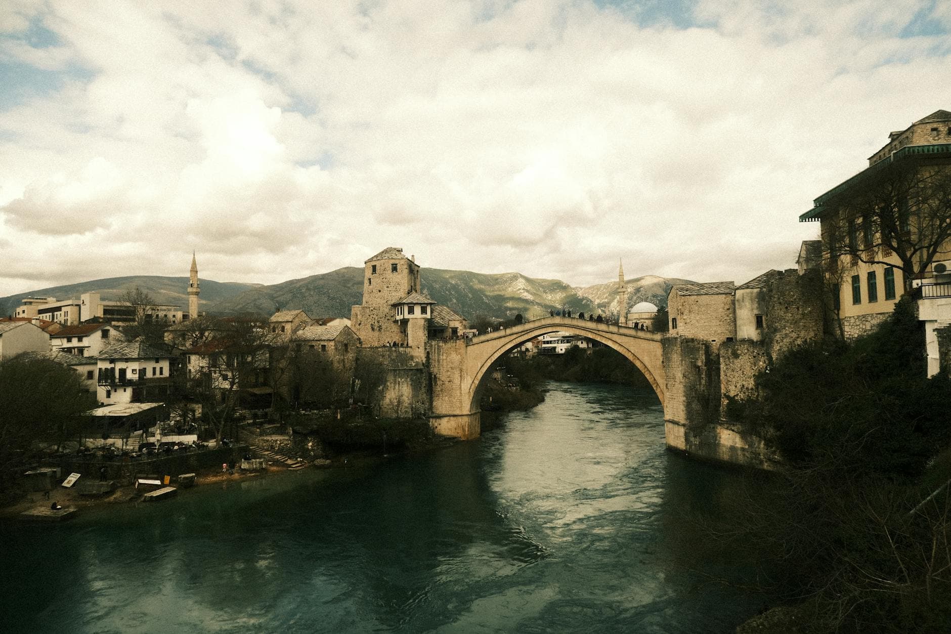 A dramatic view of the iconic Stari Most in Mostar, Bosnia, under cloudy skies.