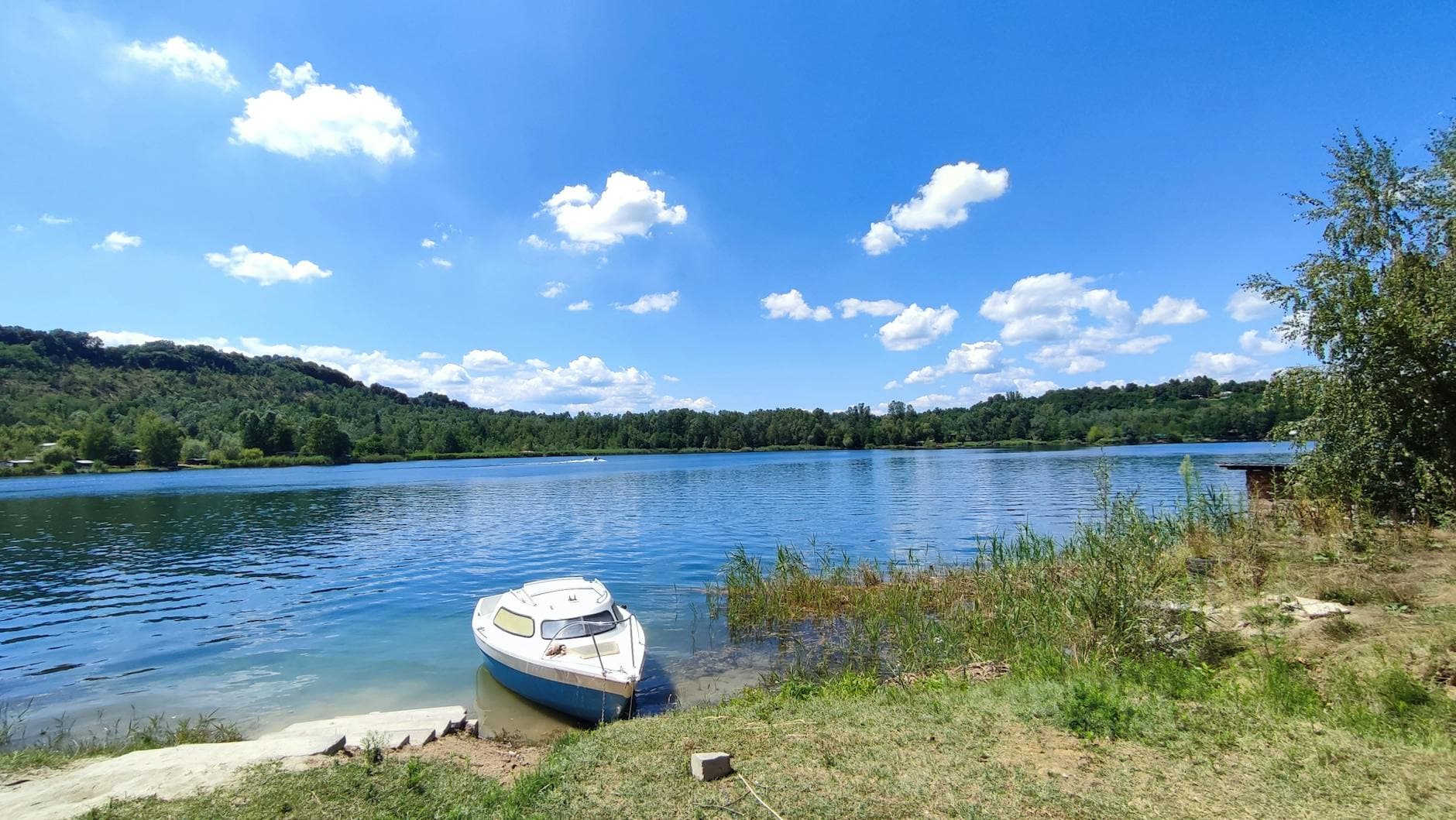A serene lake in Tuzla, Bosnia and Herzegovina, with a boat and picturesque clouds.