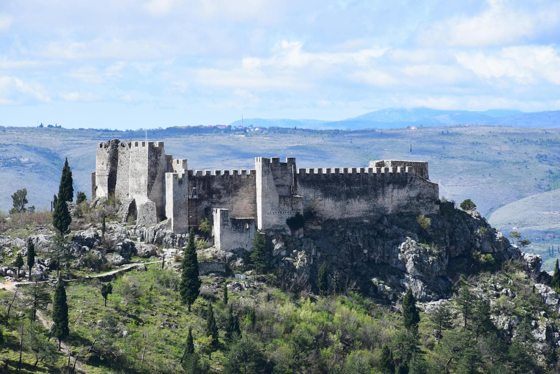 Scenic view of the medieval castle in Blagaj, Bosnia and Herzegovina, surrounded by lush greenery and mountains.