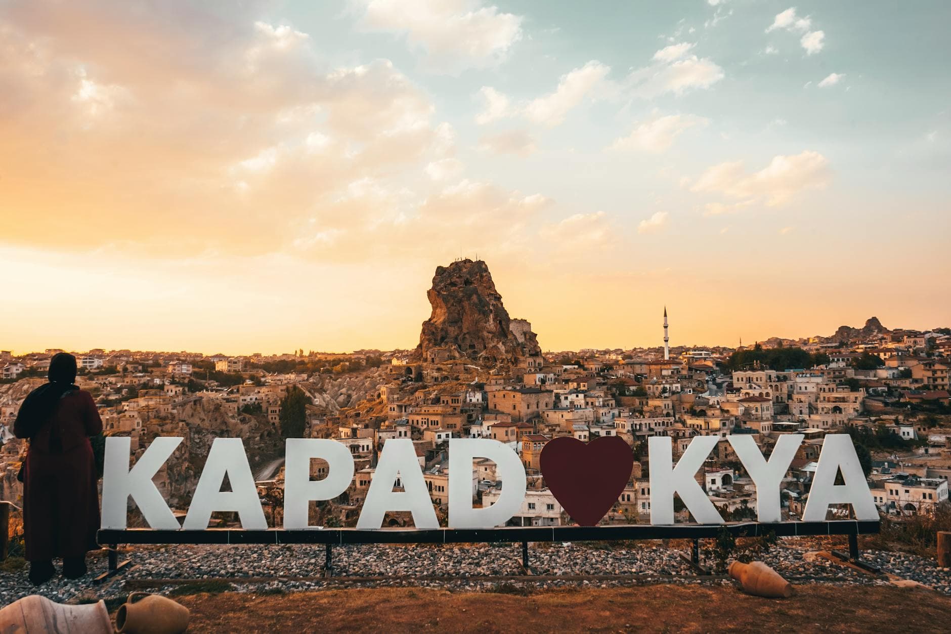 Woman enjoying a spectacular sunset view over Uchisar Castle in Cappadocia, Turkey.