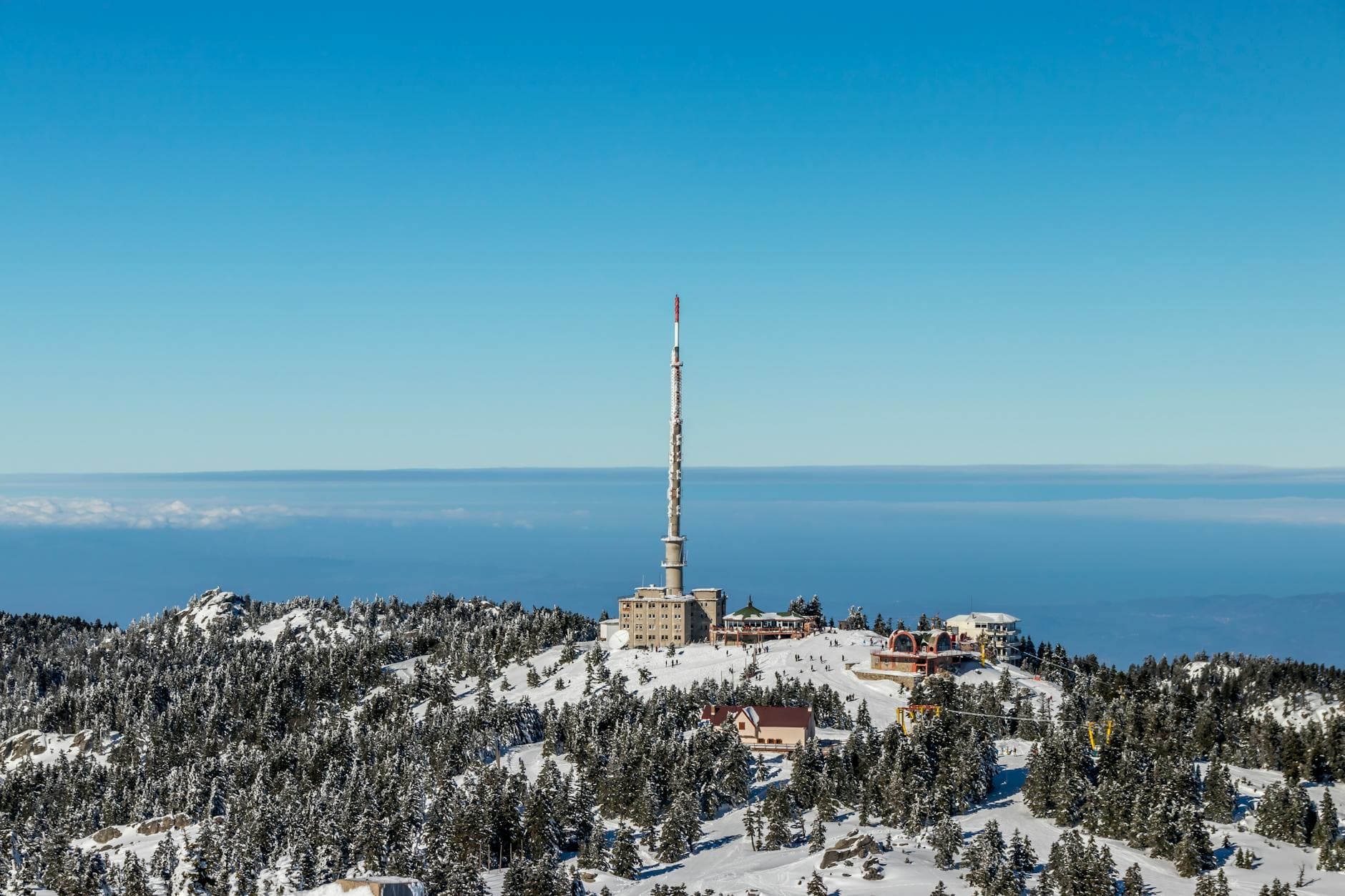 Scenic view of Uludağ TV Tower on a snow-covered peak in Bursa, Türkiye, under a clear blue sky.