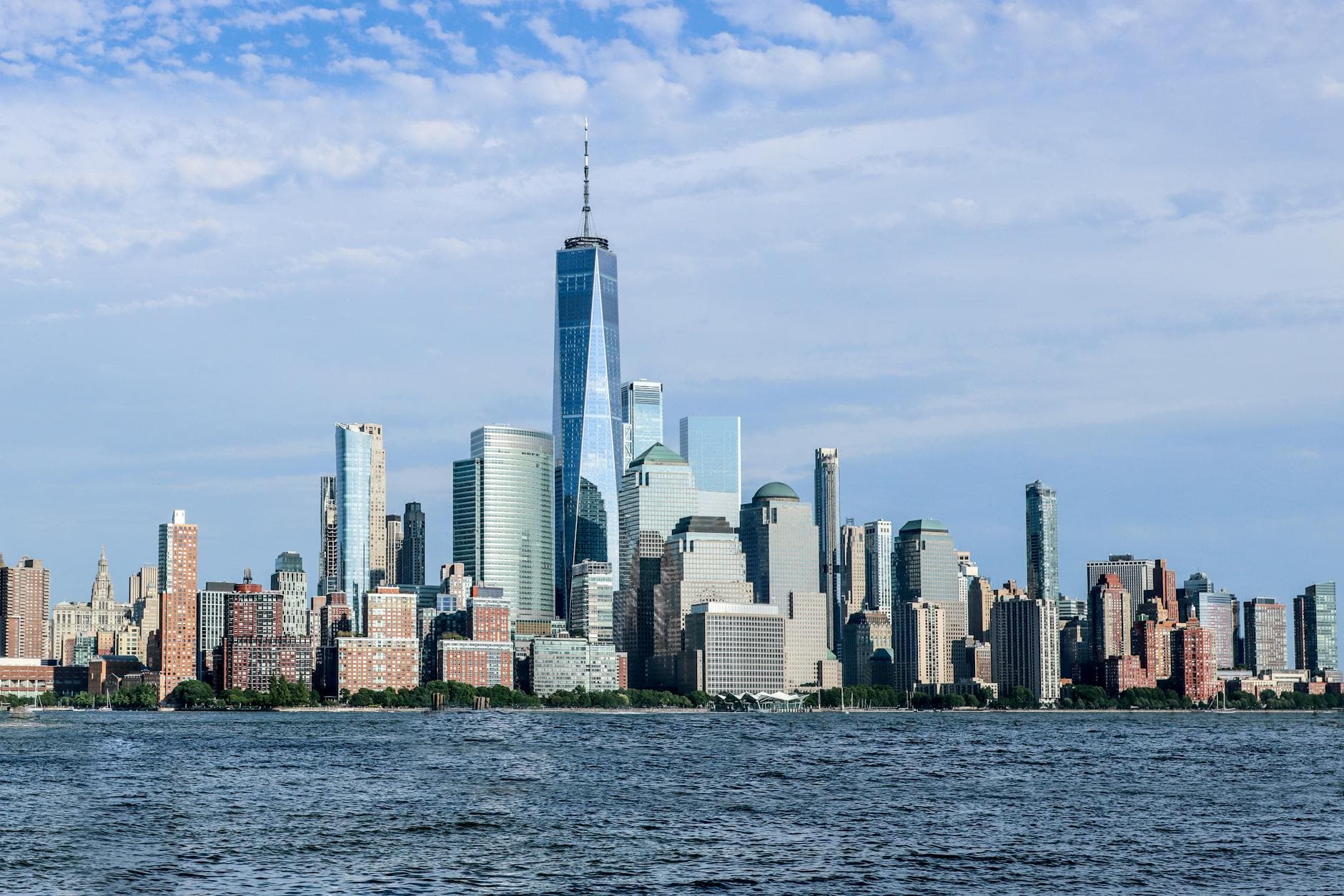 Panoramic view of Manhattan skyline featuring the iconic One World Trade Center from Jersey City waterfront.