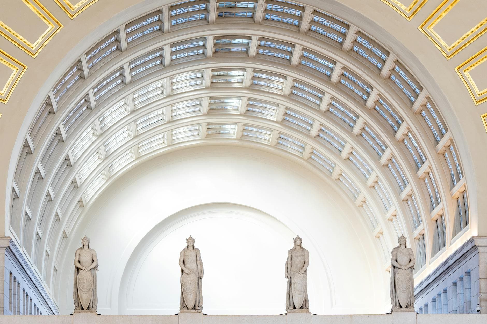Elegant indoor architectural view featuring a grand dome and statues in a historic setting.