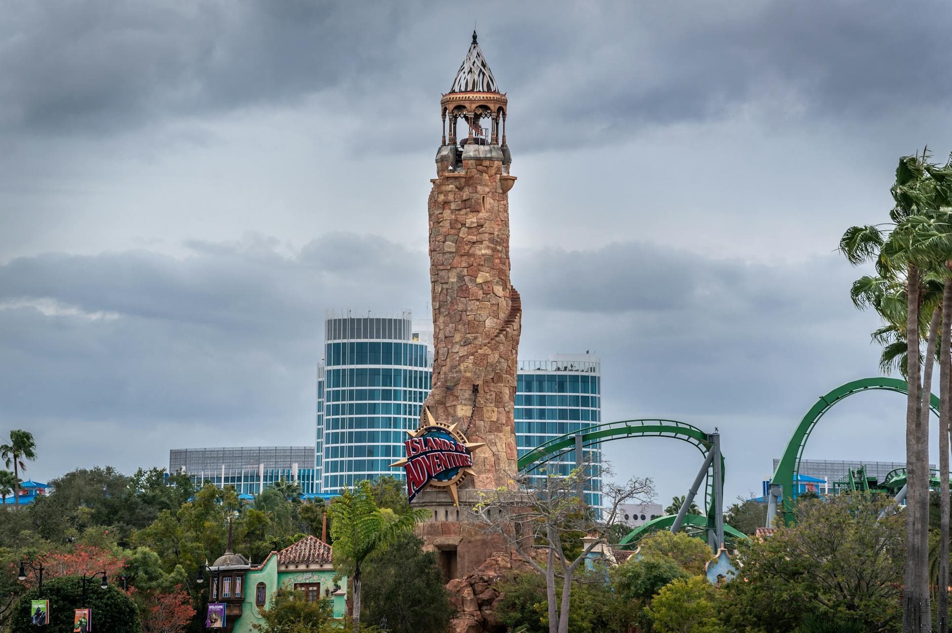 View of the famous Islands of Adventure tower amid lush greenery and roller coasters.
