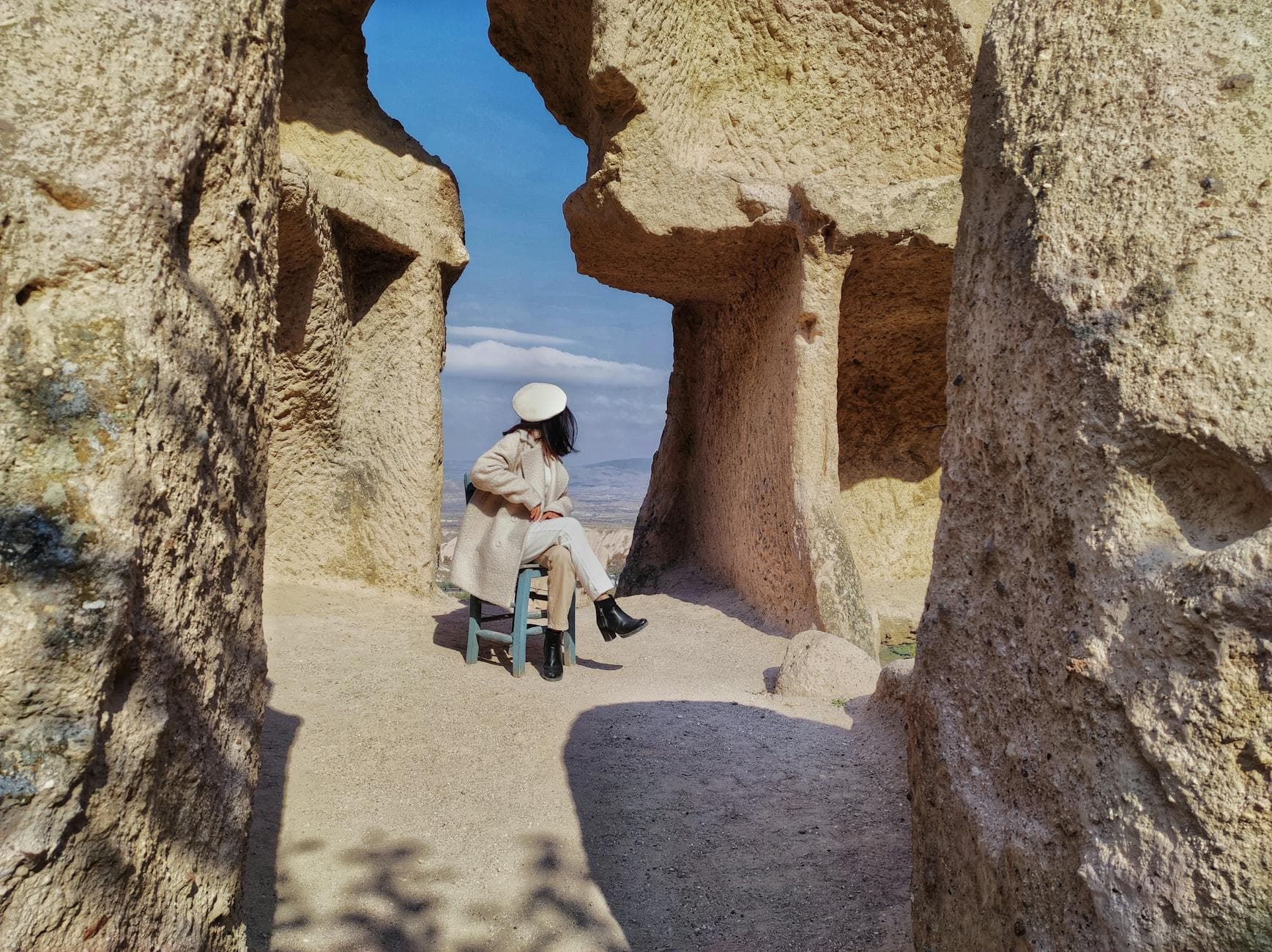 Woman sitting in ancient rock formations in Ürgüp, Nevşehir, Türkiye, surrounded by majestic geology.