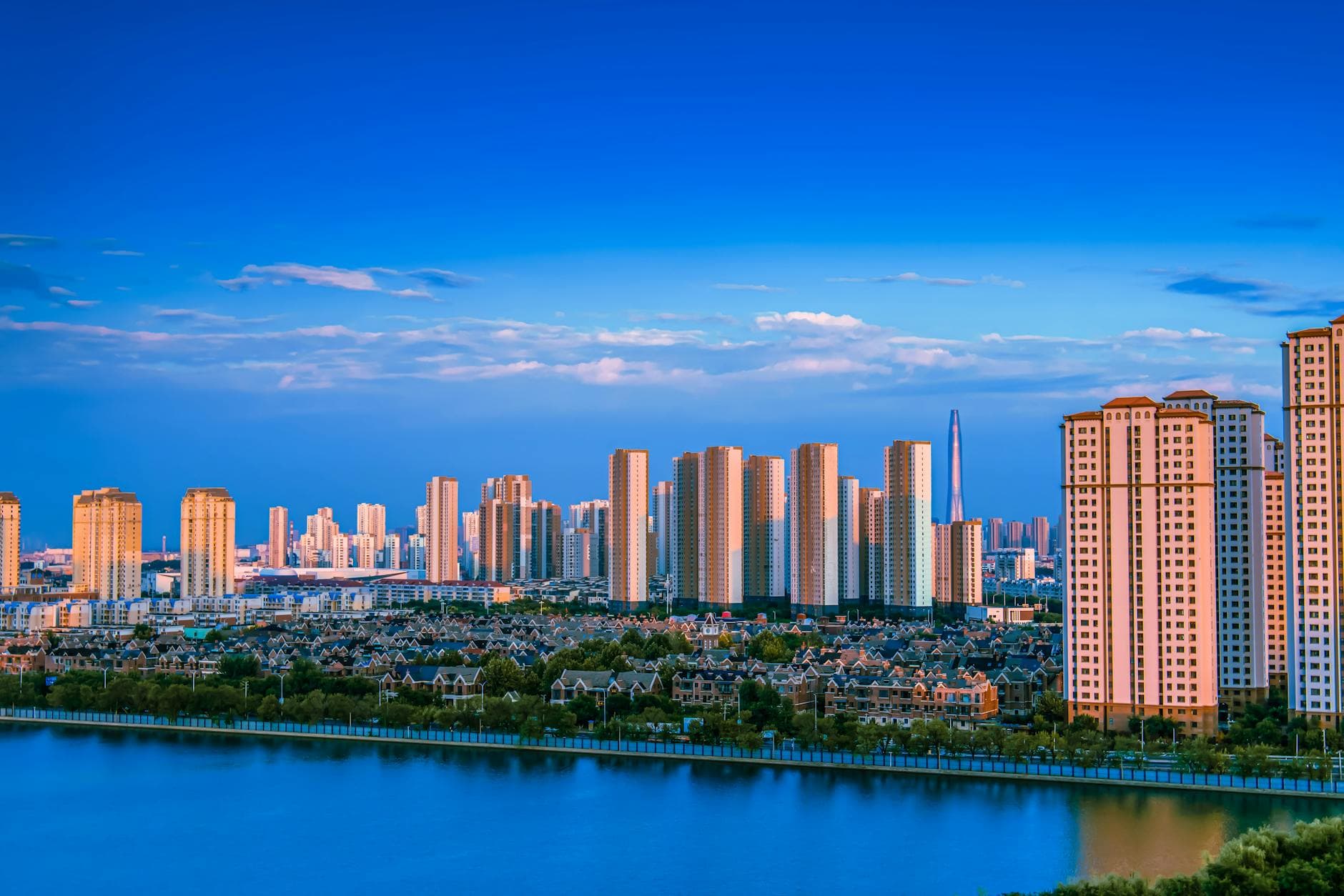 Stunning view of a modern city skyline reflecting on a tranquil waterfront under a blue sky.