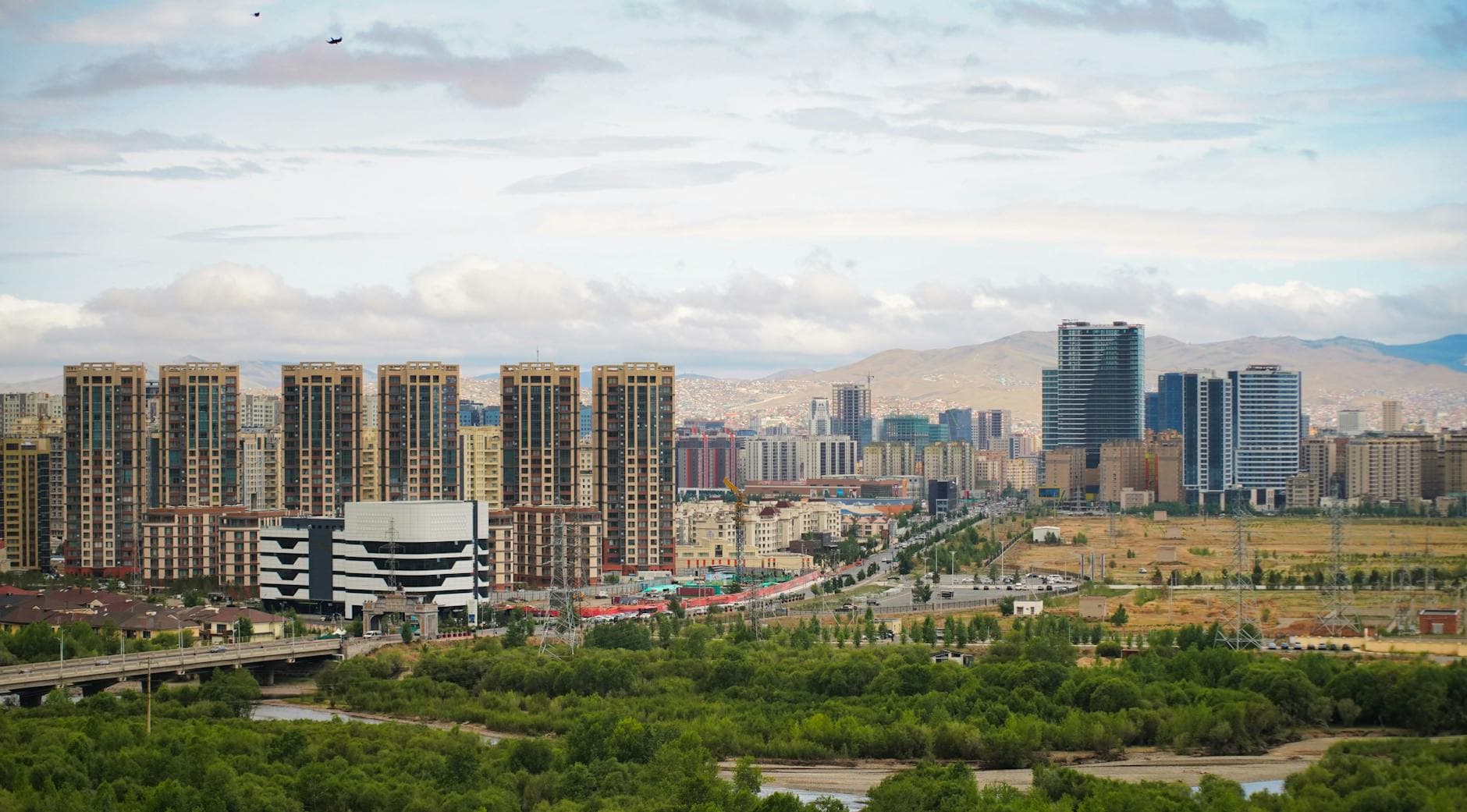 Panoramic view of Ulaanbaatar's urban skyline and lush landscape under a cloudy sky.