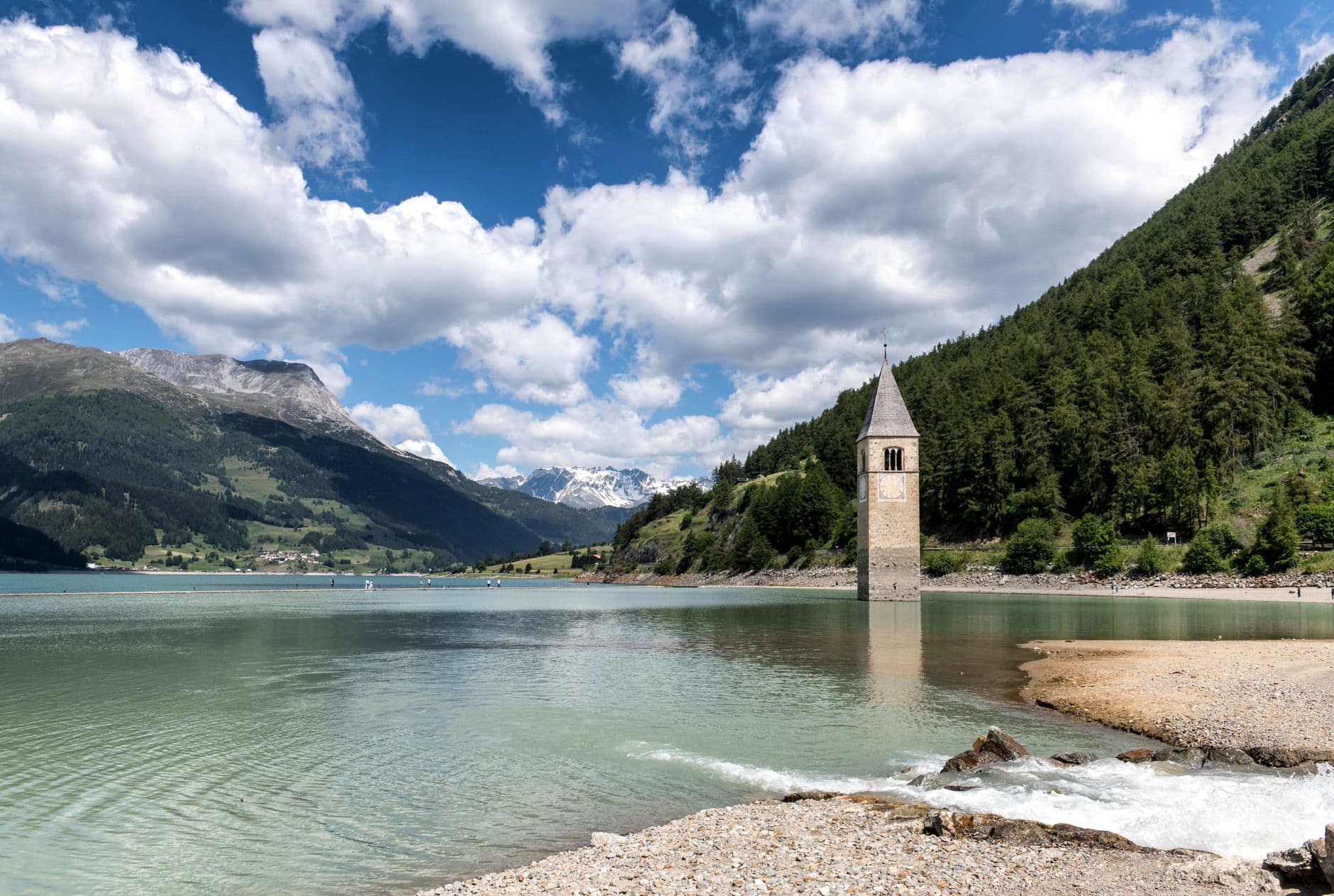 Picturesque view of Campanile di Curon submerged in Reschen Lake, surrounded by Alps.
