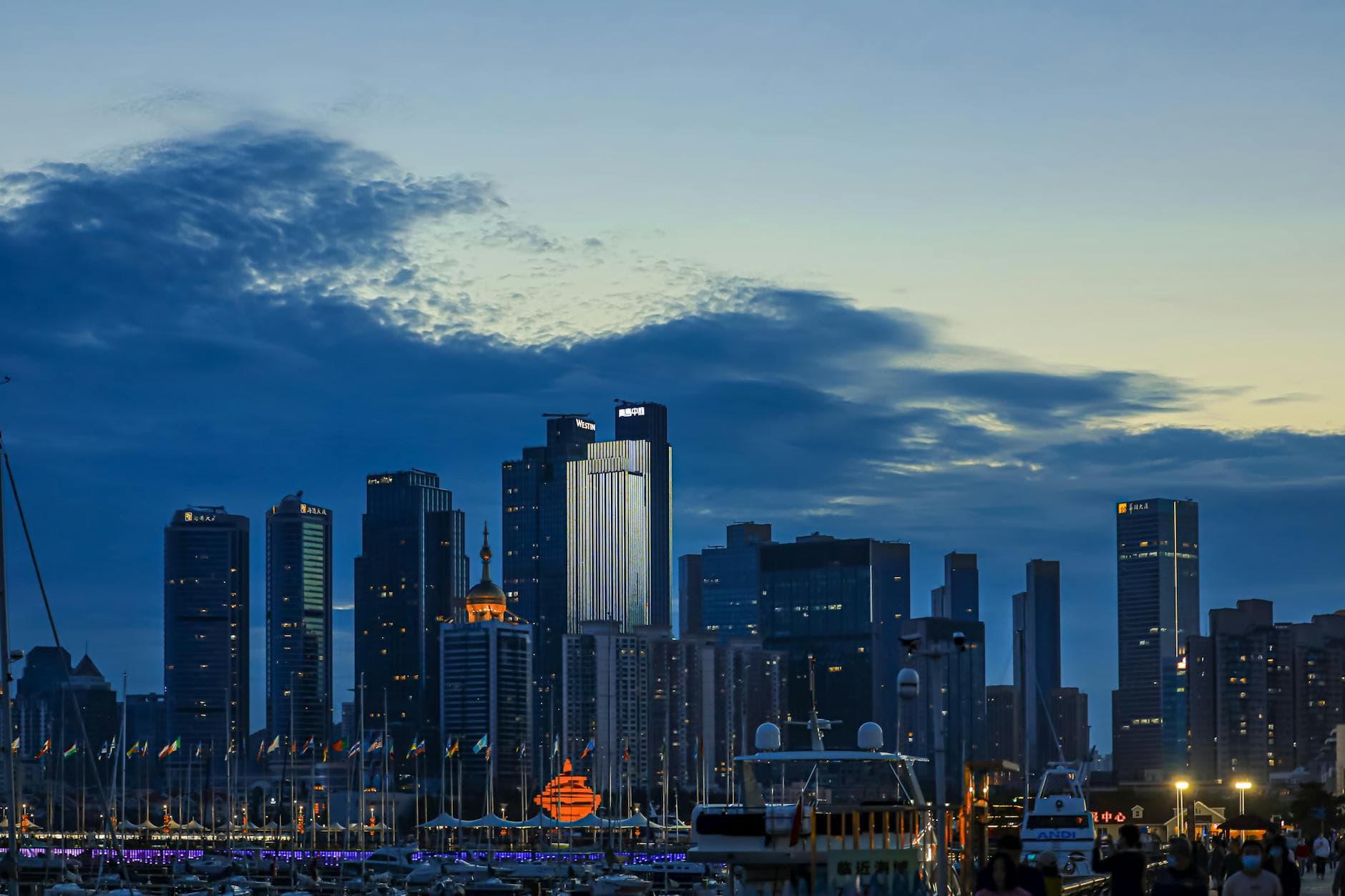 Stunning dusk view of a modern city skyline with illuminated skyscrapers reflecting on waterfront.