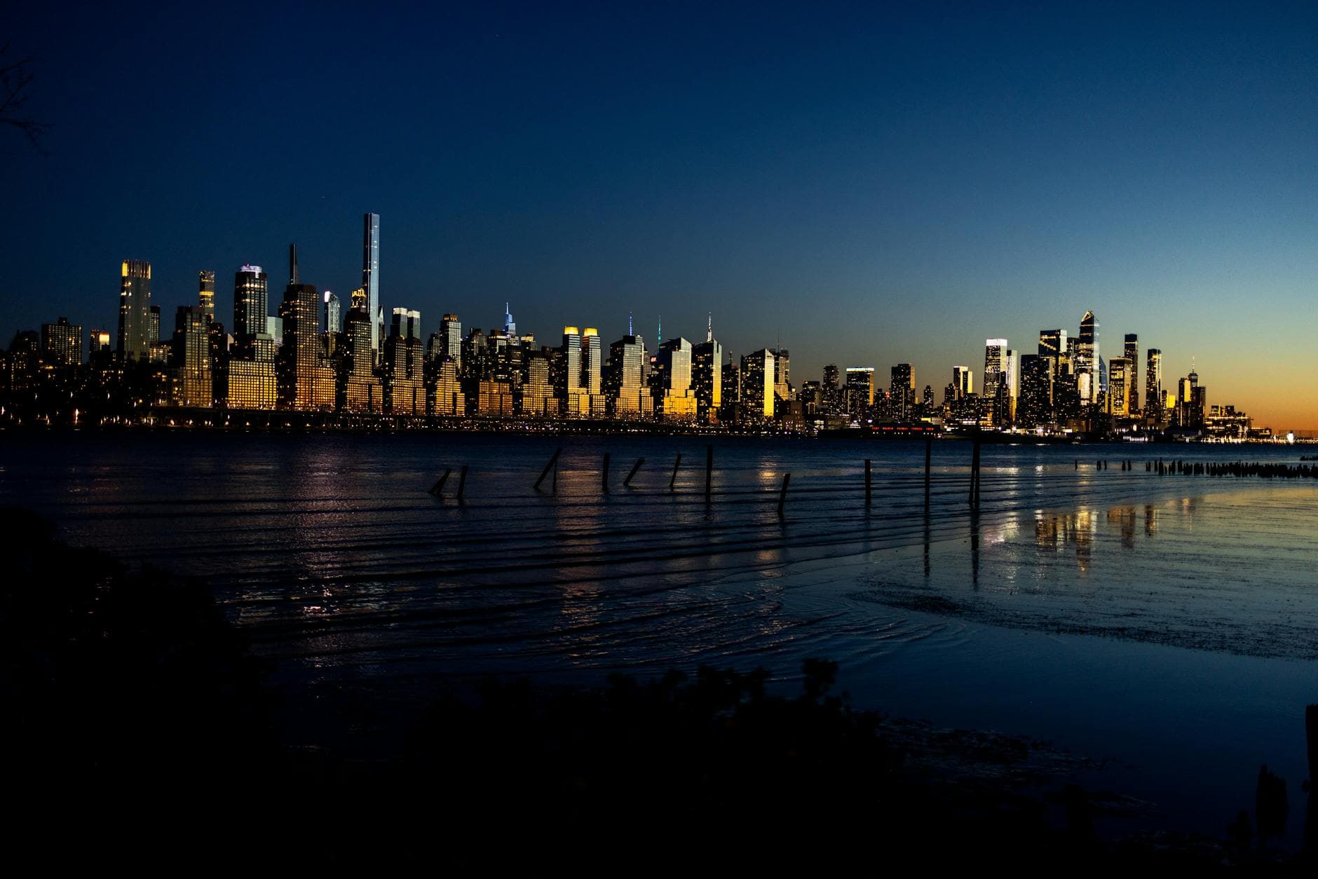 A captivating view of the illuminated Manhattan skyline reflecting on the water at twilight.