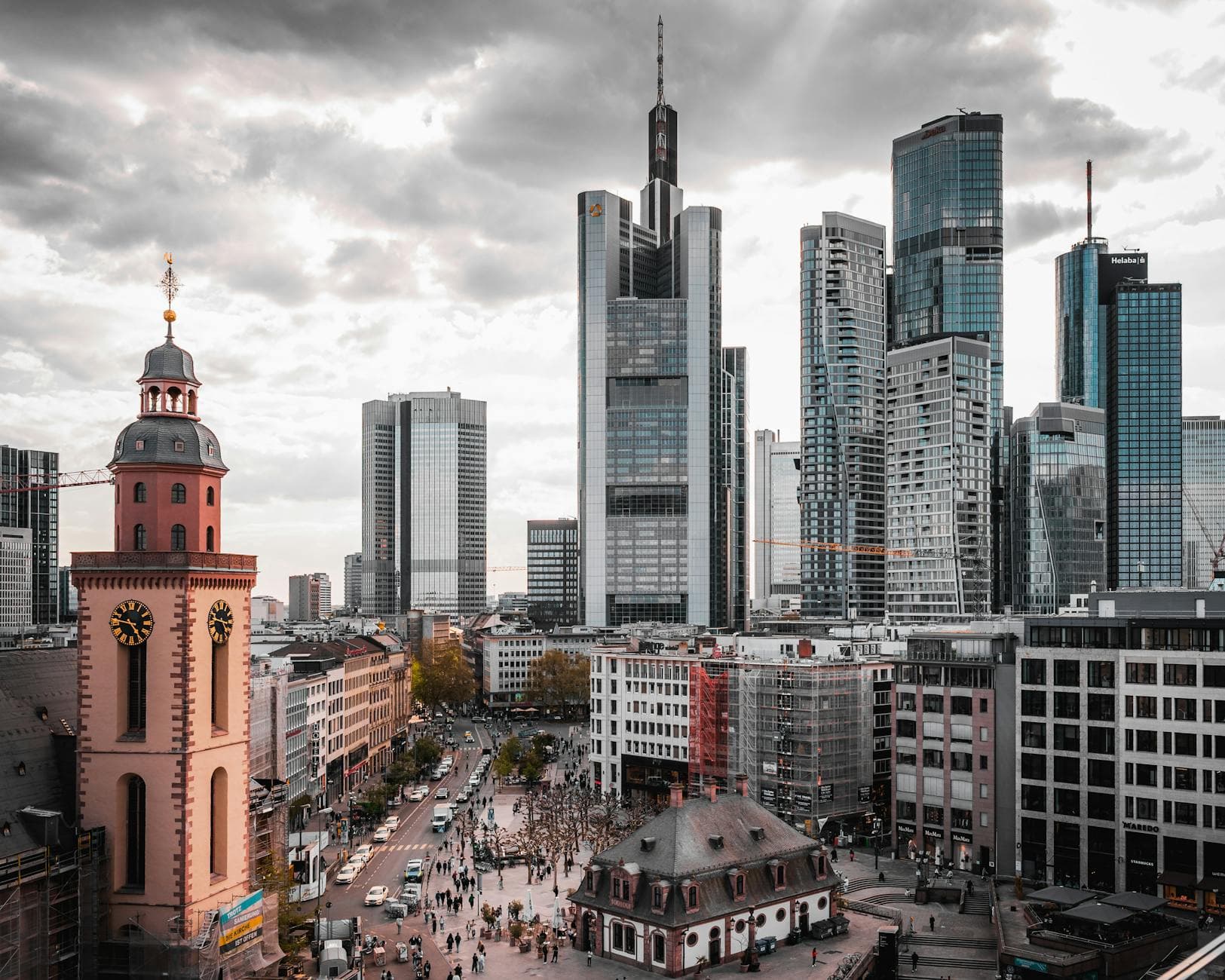 A stunning view of Frankfurt's skyscrapers and historical church under a cloudy sky.