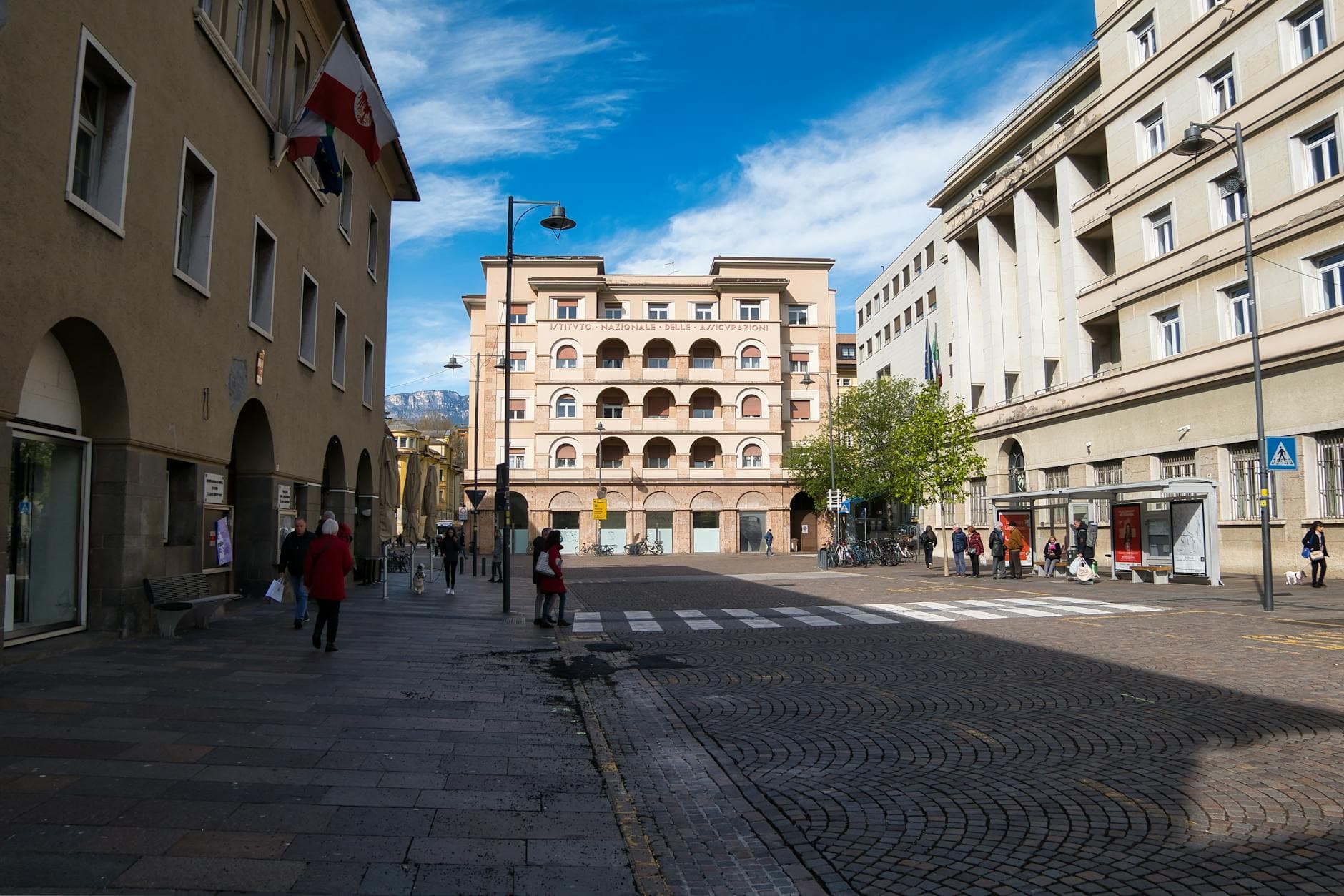 Sunny day on a city street in Bozen, featuring historic architecture and pedestrian activity.