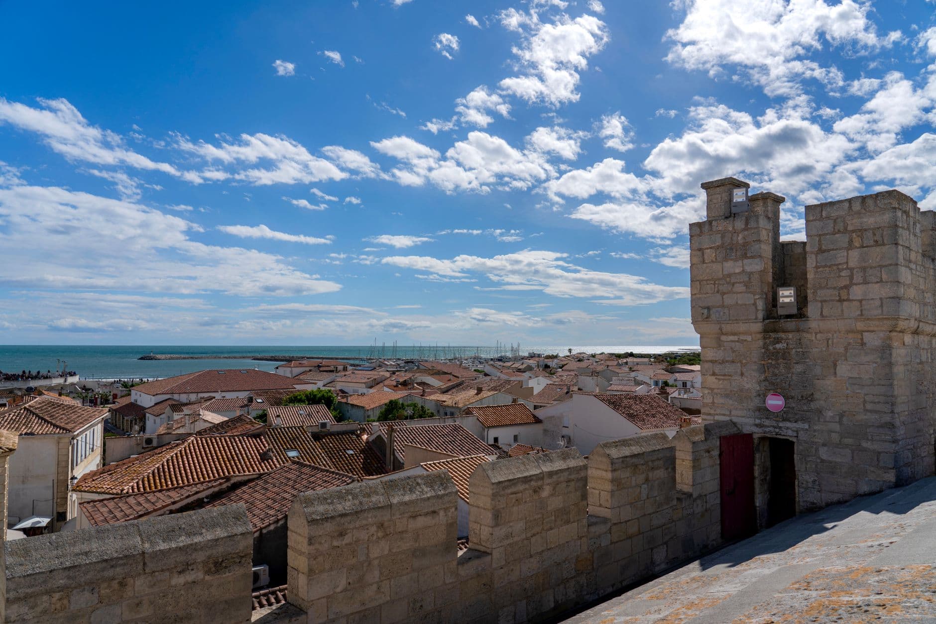 A picturesque coastal town with historic stone tower under a bright blue sky.