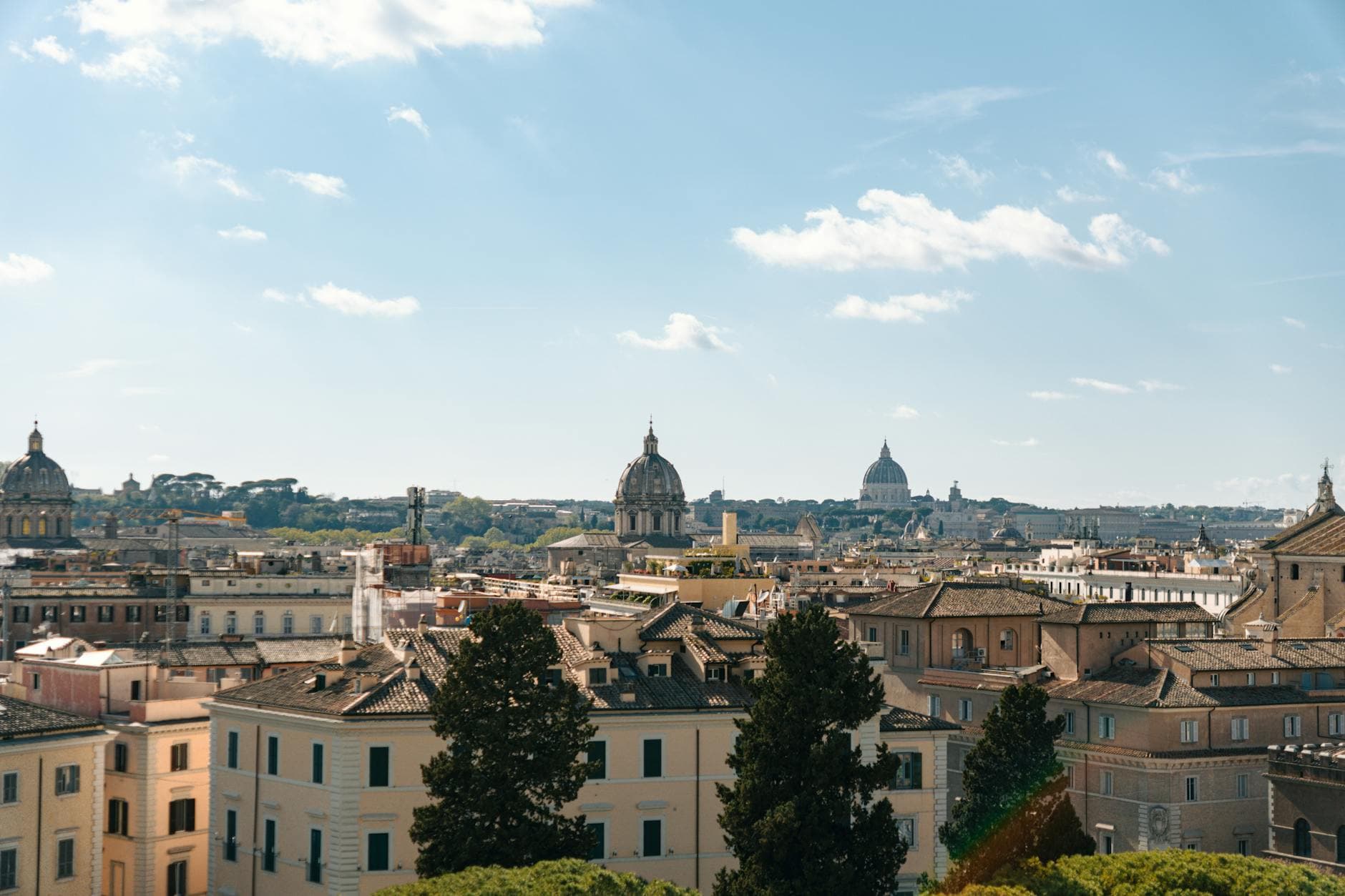 Expansive view of Rome's historic skyline featuring domes and classic architecture under a clear blue sky.