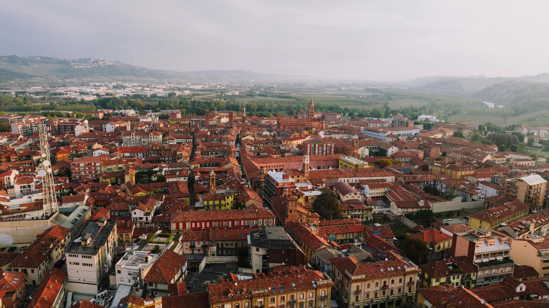 Captivating aerial view of Alba, Italy's historic district with red tile roofs and scenic hillsides.