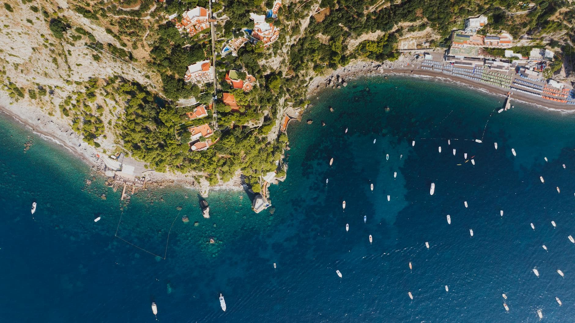 Stunning aerial view of Positano coast with boats and lush landscape.