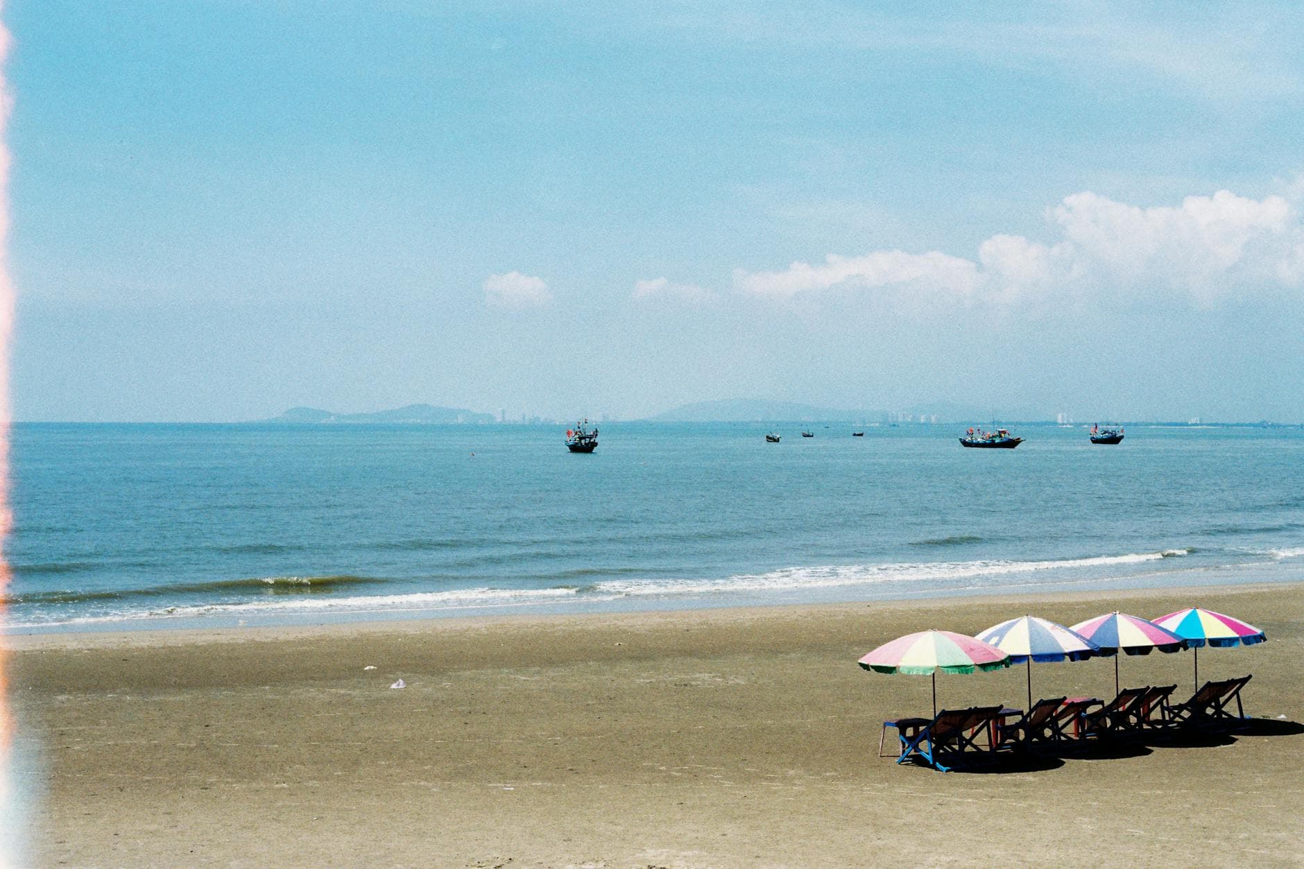 Relaxing beachfront view with umbrellas and chairs on a sunny day in Ba Ria - Vung Tau, Vietnam.