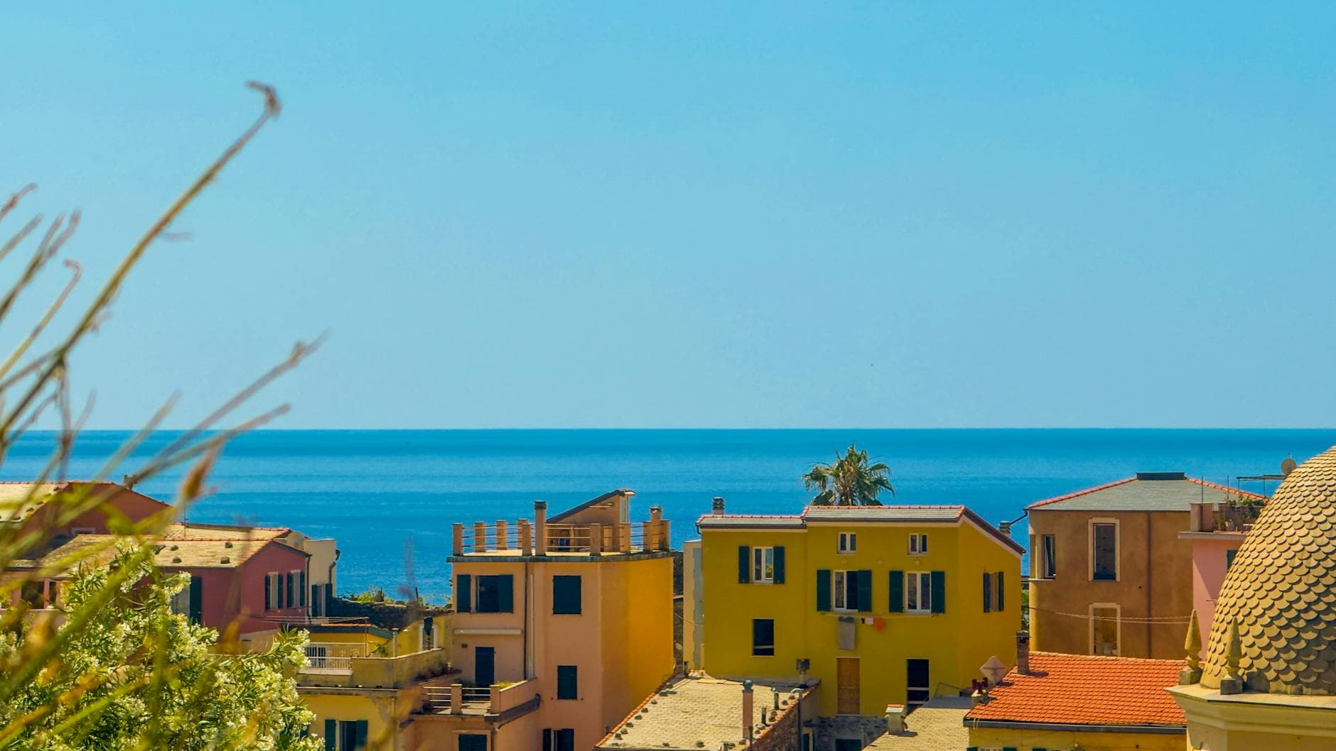 Vibrant buildings in an Italian coastal town with clear blue sea and sky.