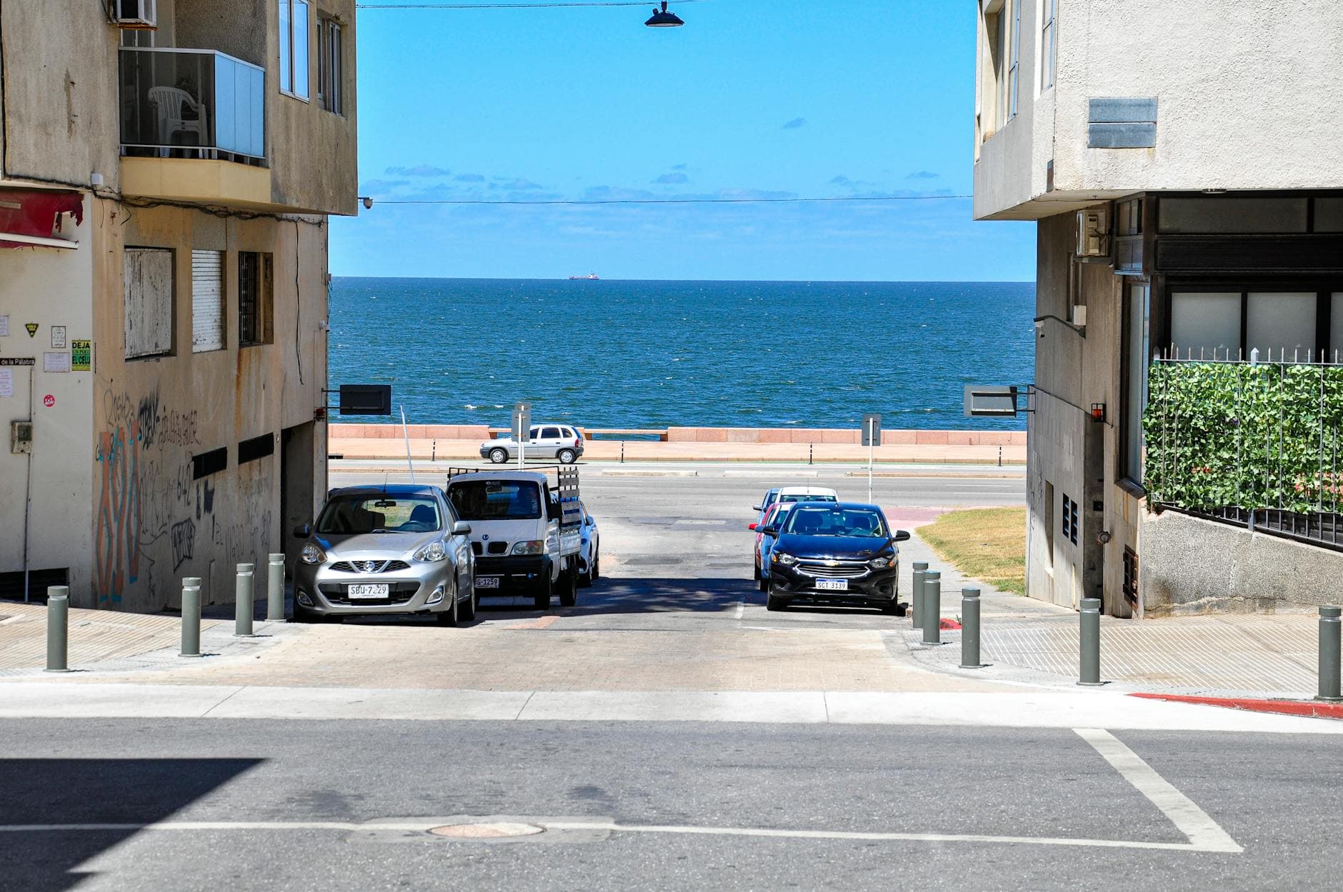 Urban street scene in Montevideo, Uruguay, featuring parked cars and a view of the waterfront.