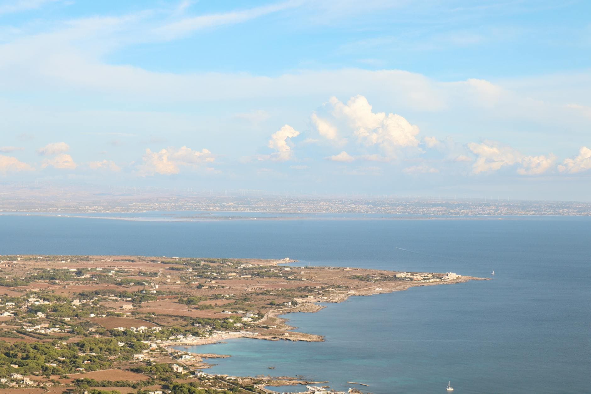 Scenic aerial view of Sicily's coastline under bright summer skies.