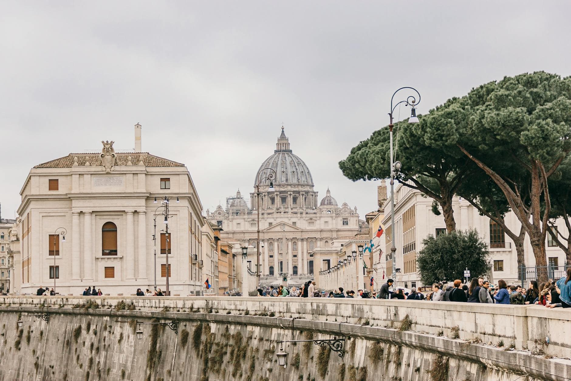 Scenic view of St. Peter's Basilica from a bustling street in Vatican City, capturing architecture and daily life.