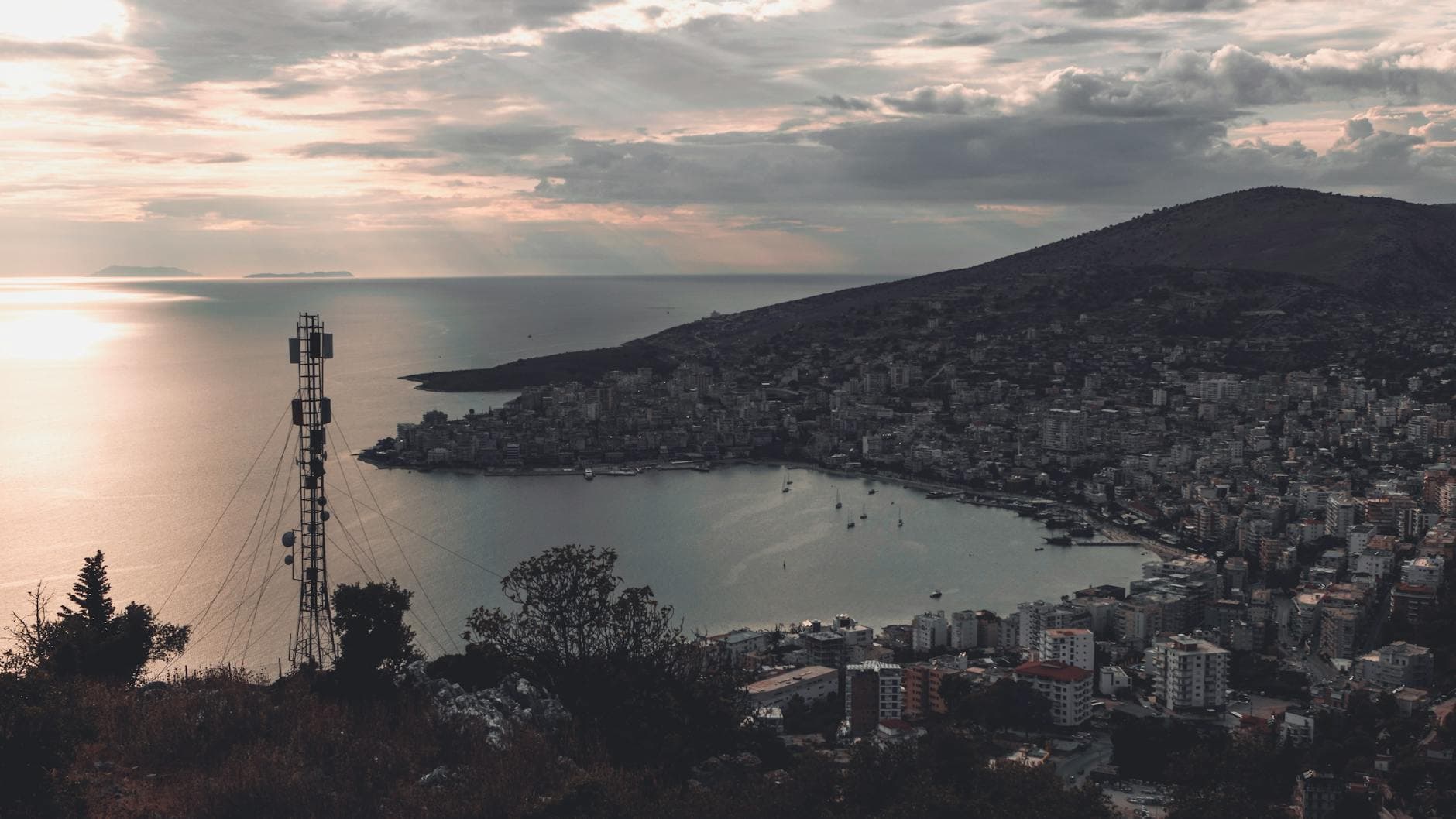 A serene view of Saranda, Albania cityscape and coastline at dusk with a distant television tower.