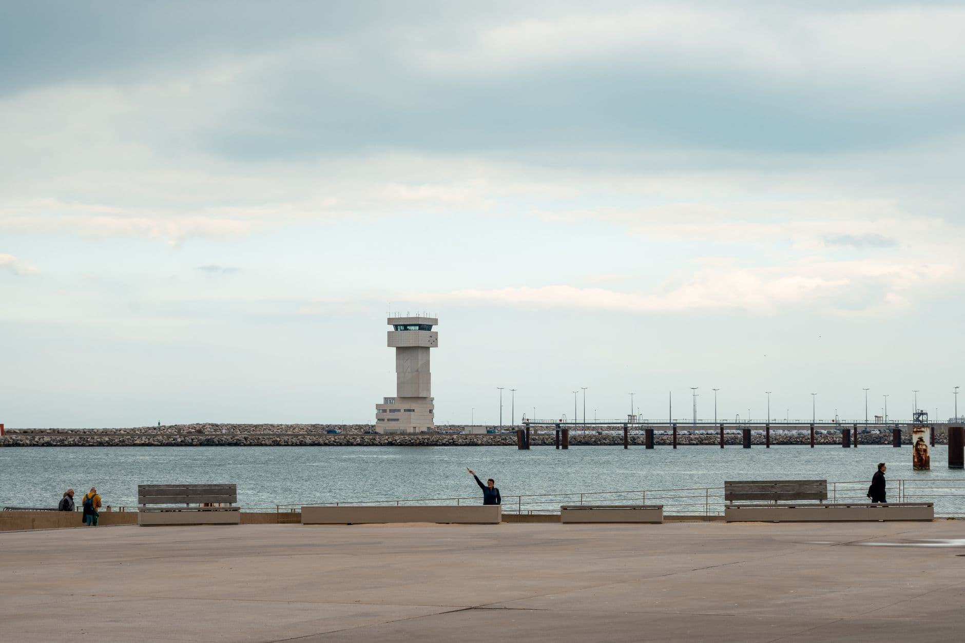 Serene coastal scene featuring a pier and observation tower in Calais, France.