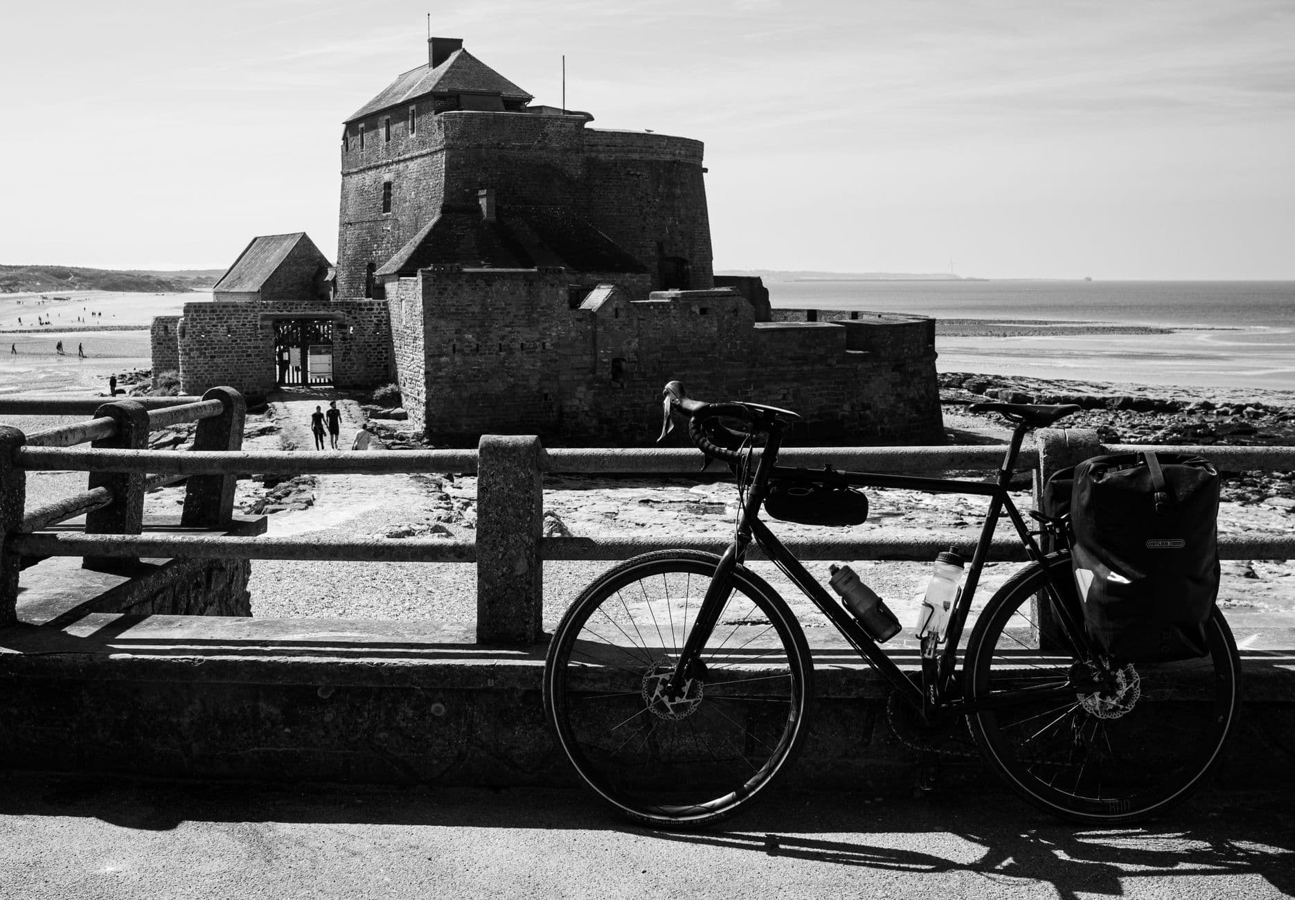 Monochrome photo of a bicycle near Fort National, Saint-Malo, France. Scenic coastal view.