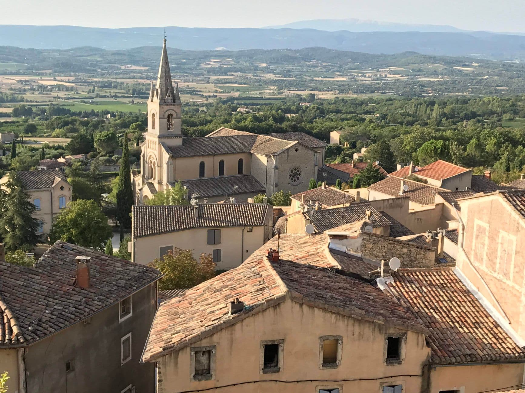 A picturesque view of Saignon's historic church and surrounding countryside in Provence, France.